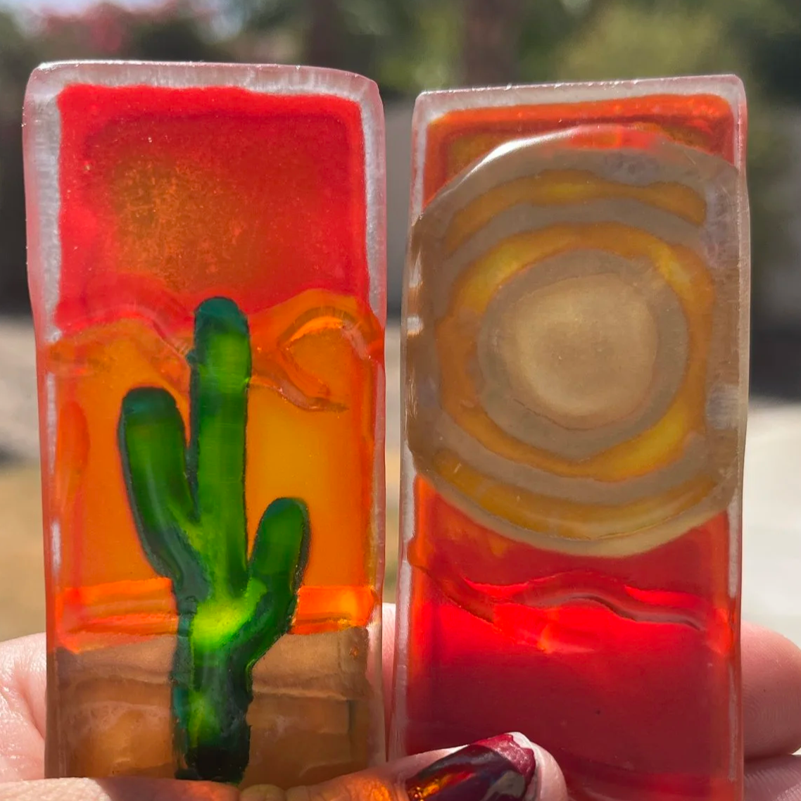 Two small rectangular textured glass art pieces featuring a cactus and desert sunset design