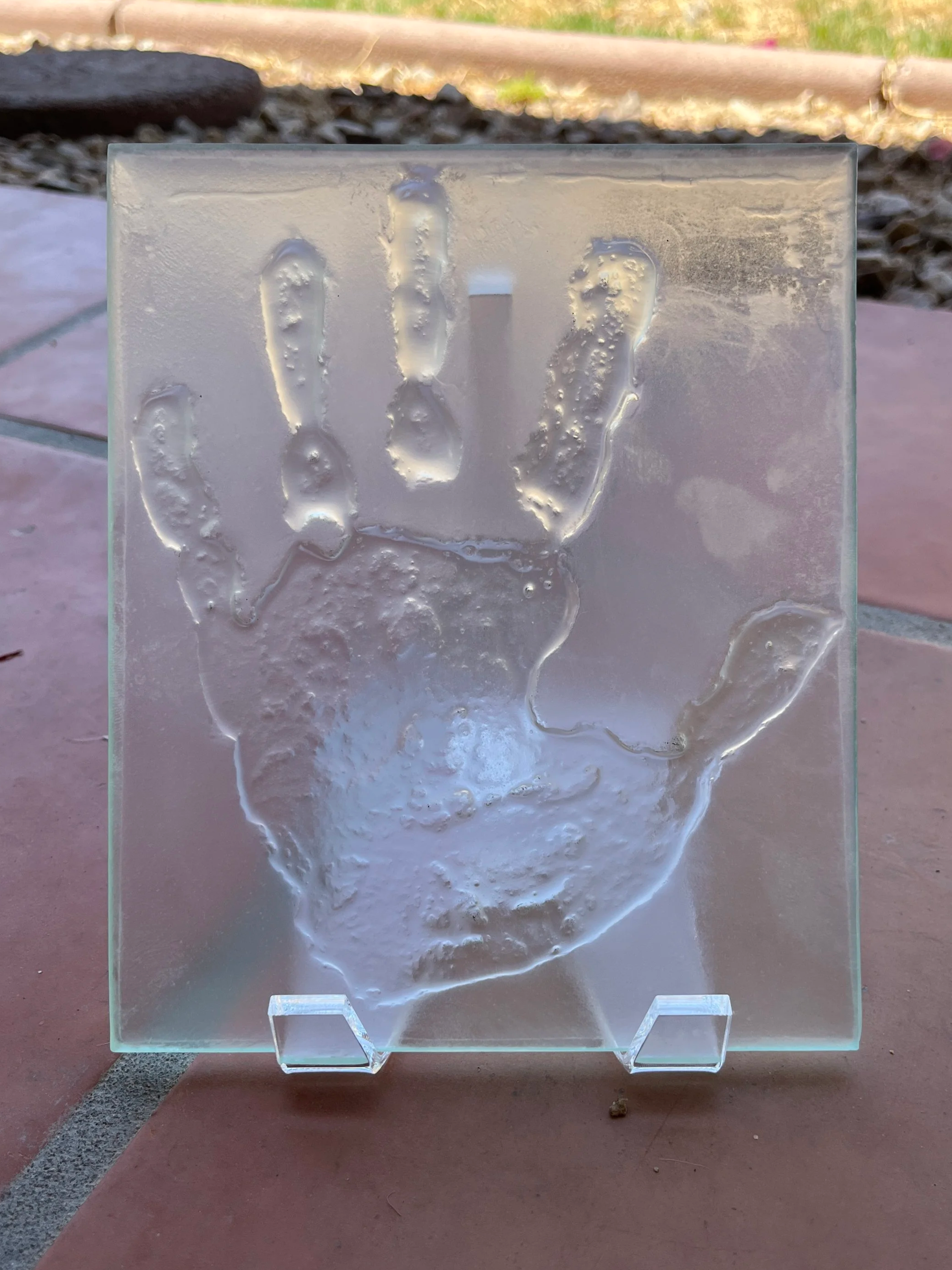 A large handprint imprinted on glass tile
