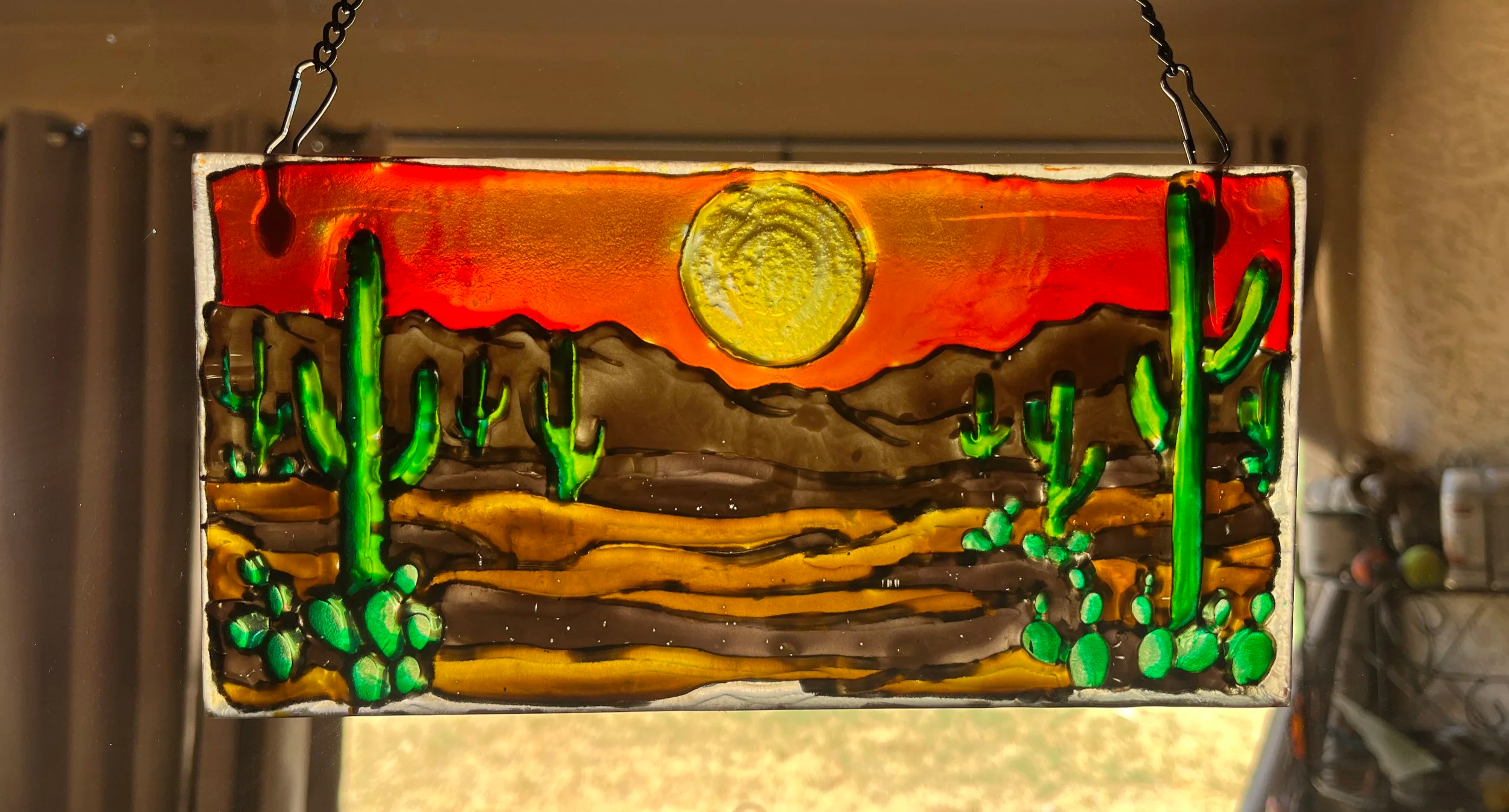 A rectangular textured glass suncatcher painted with a desert sunset design
