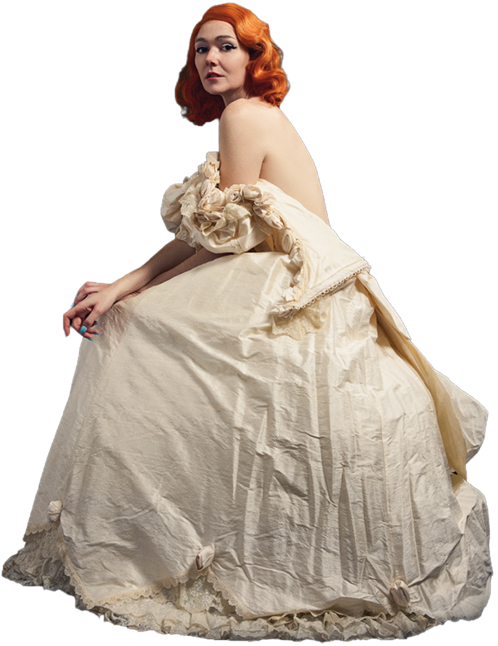 A woman with red hair in an elegant vintage cream-colored dress seated with her arms resting on her lap.