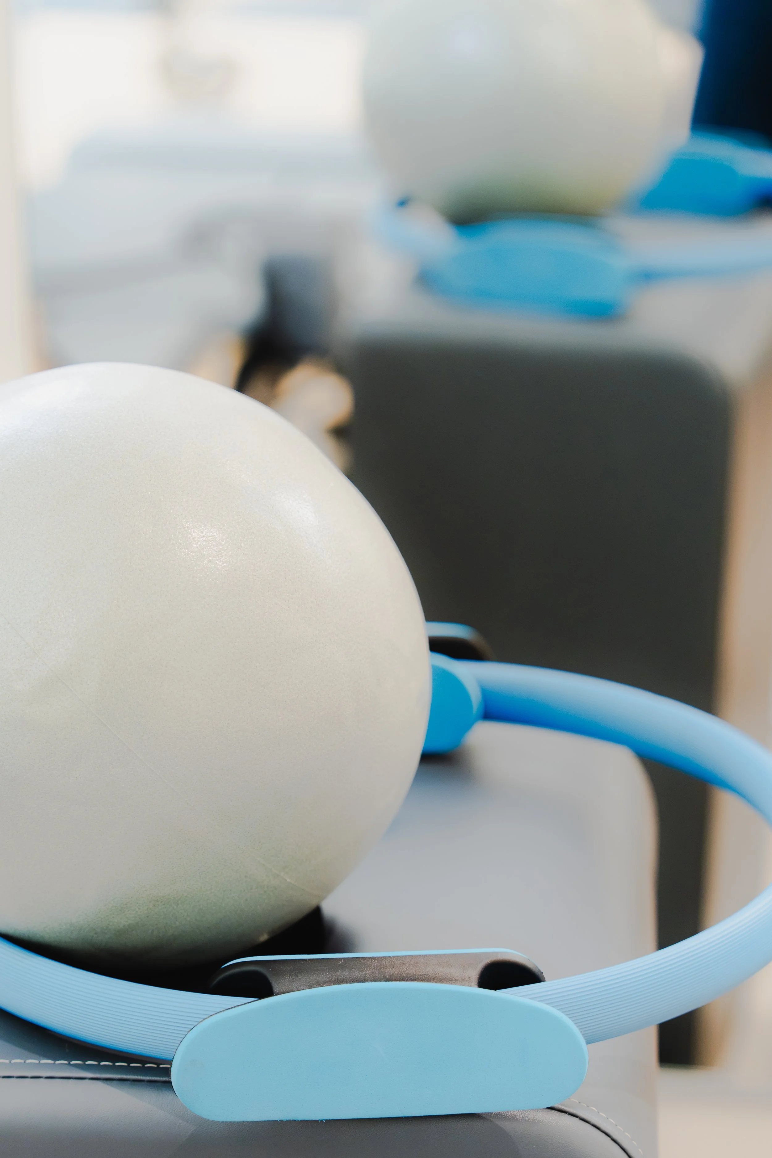 Une box de pilates reformer avec un ballon blanc et des cercles de fitness .