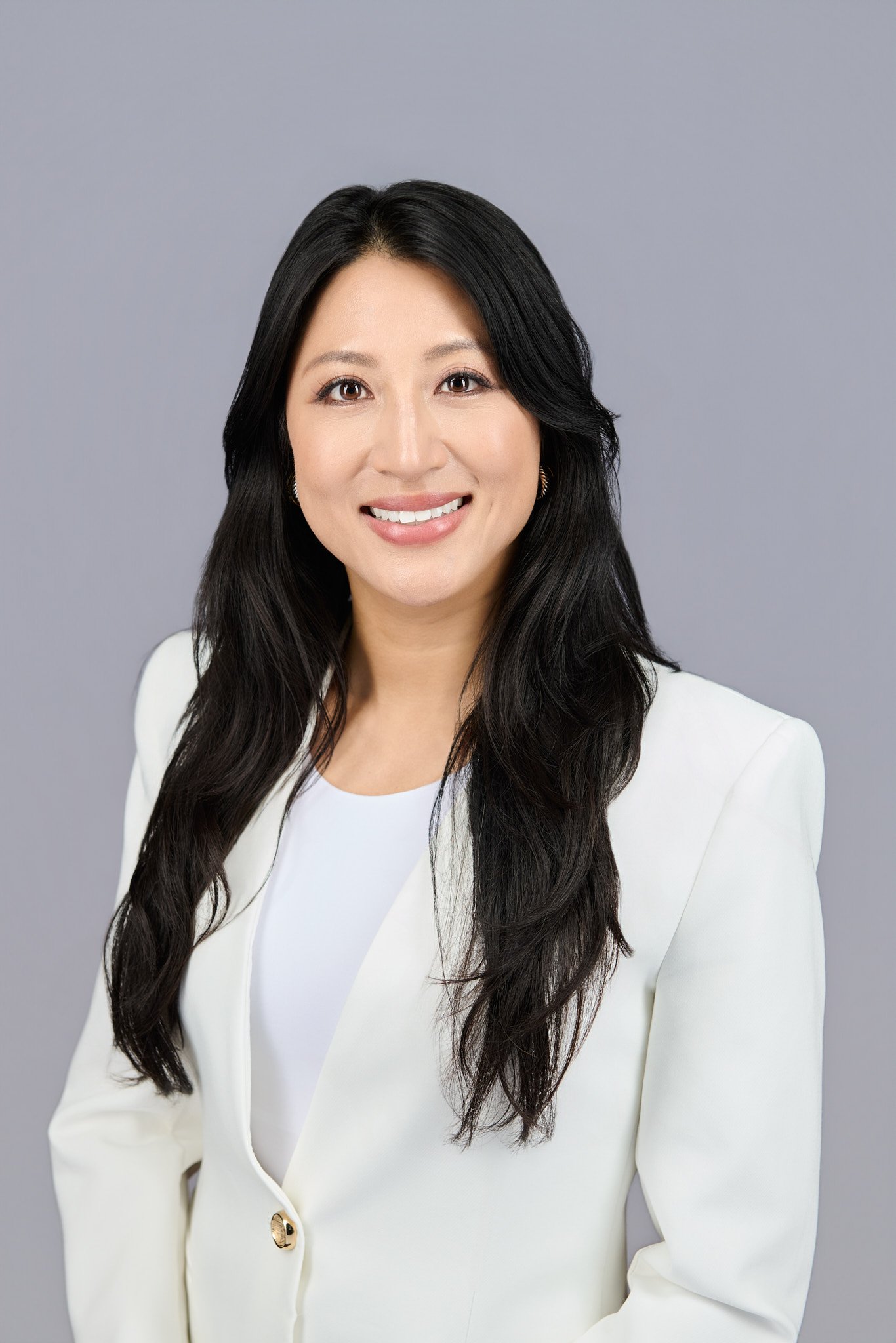 Milly Yee, smiling against a plain grey background.