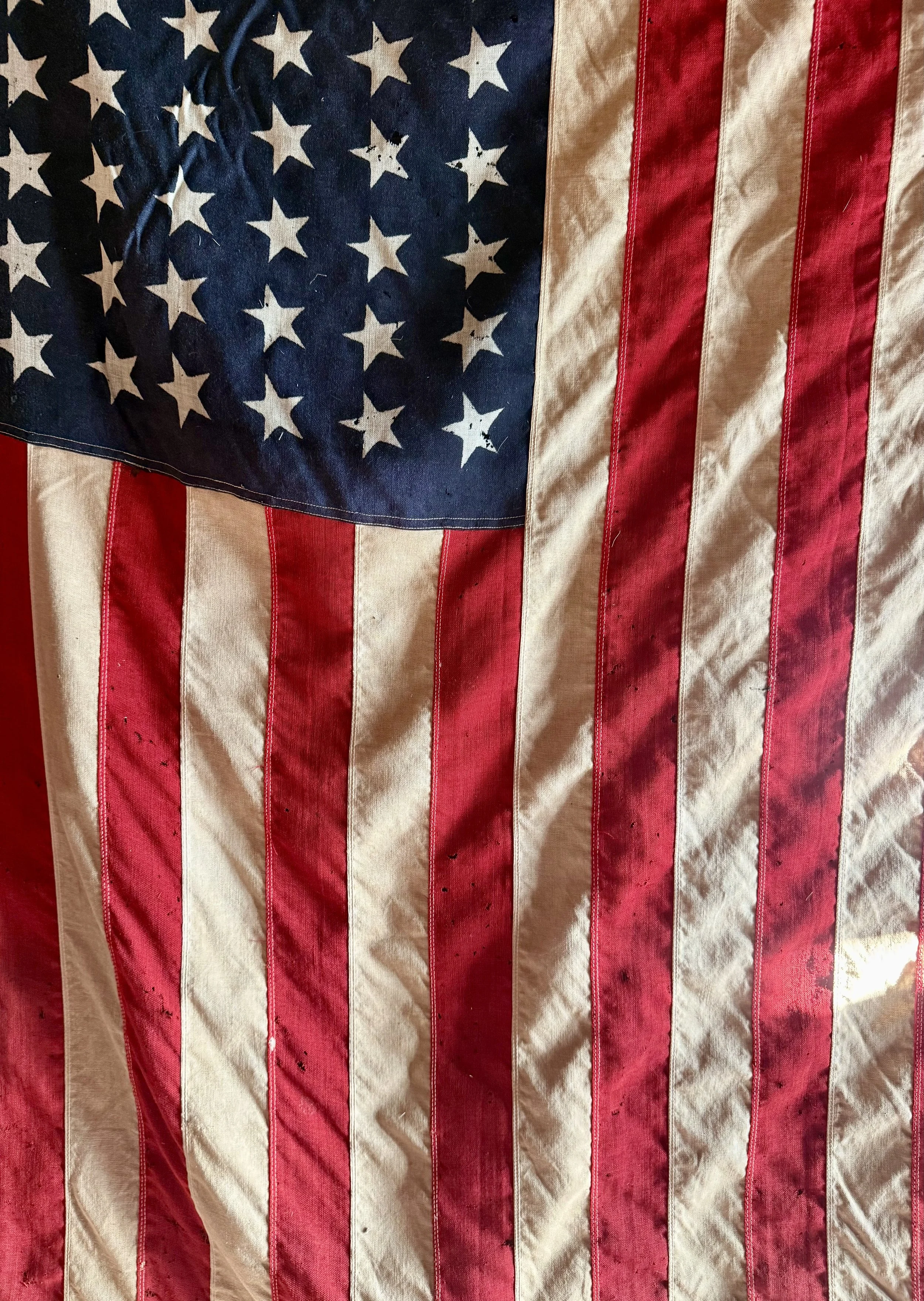 Close-up of an American flag with worn and faded red and white stripes, and a blue field with white stars.