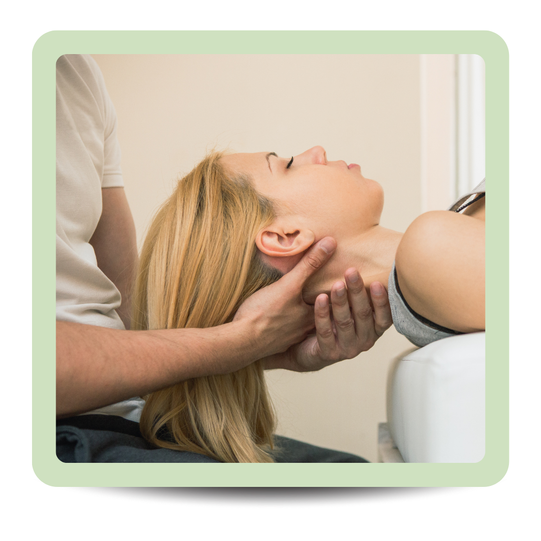 A woman sitting on a bed, holding her stomach with both hands, appearing to be in pain or discomfort.