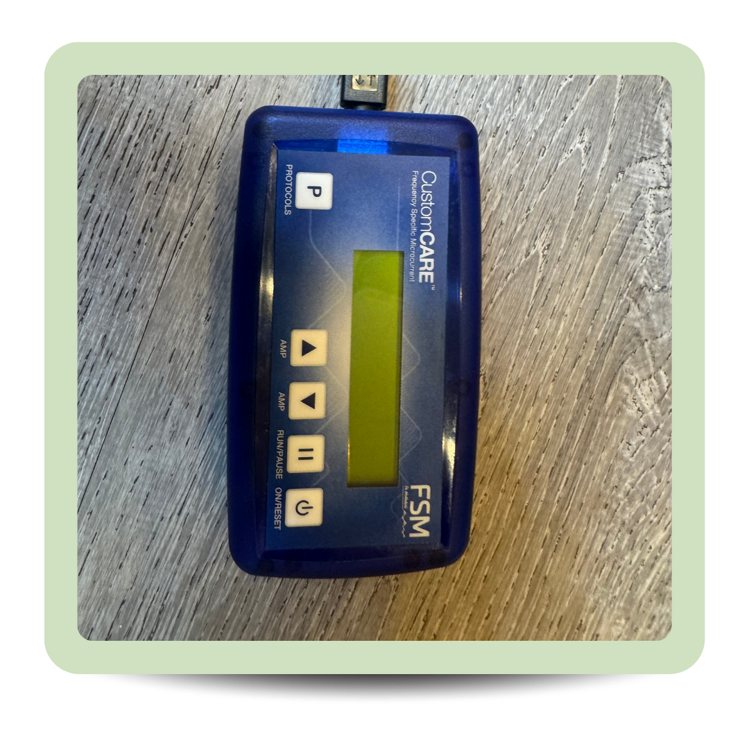 A blue medical device labeled CustomCARE FSM with buttons and a small screen on a wooden surface.
