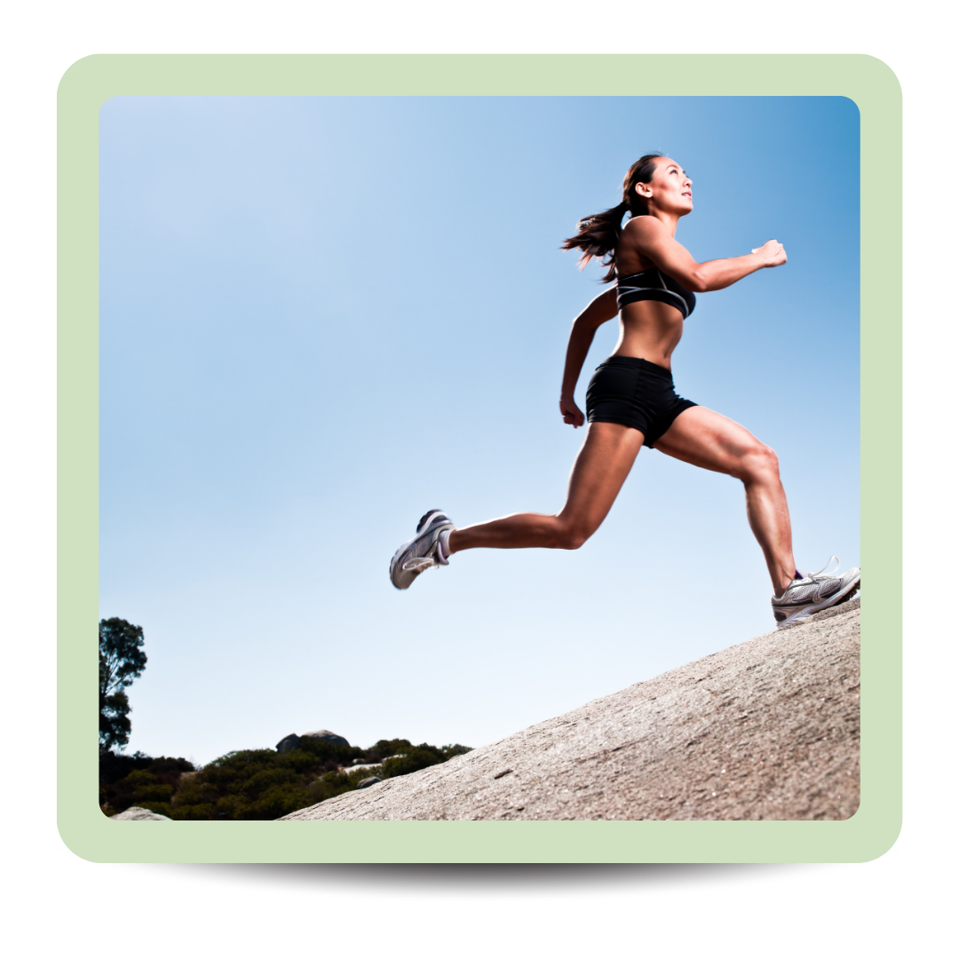 A woman wearing black athletic wear running uphill on a rocky surface outdoors against a blue sky.