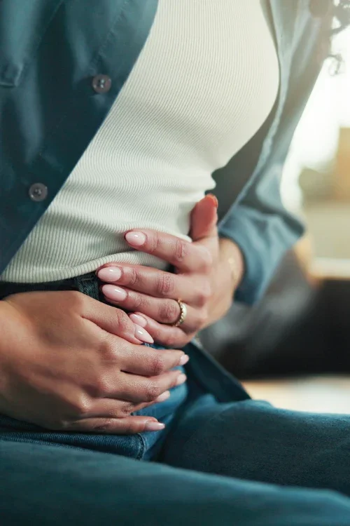 Person clutching their stomach, possibly indicating pain or discomfort.