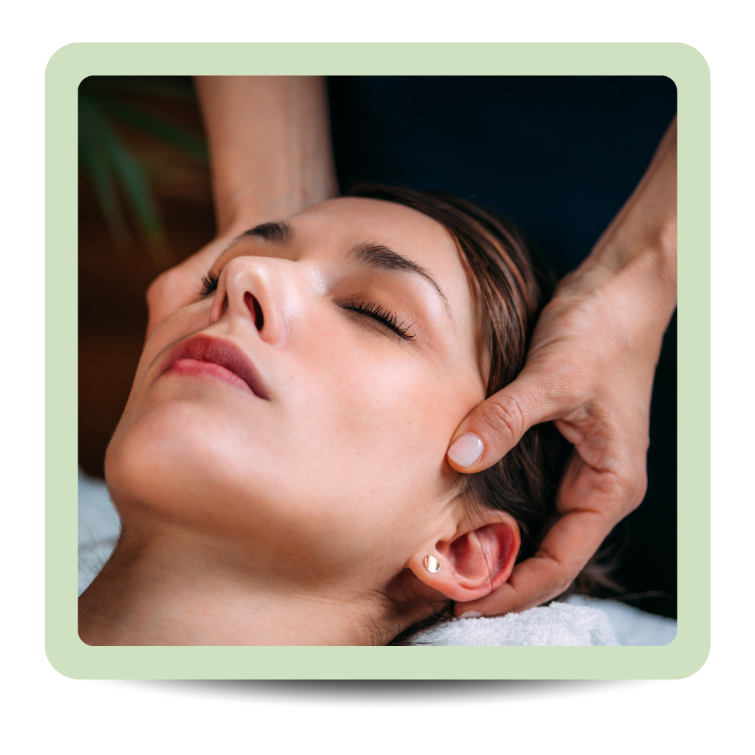 Close-up of a woman receiving a facial massage with her eyes closed.