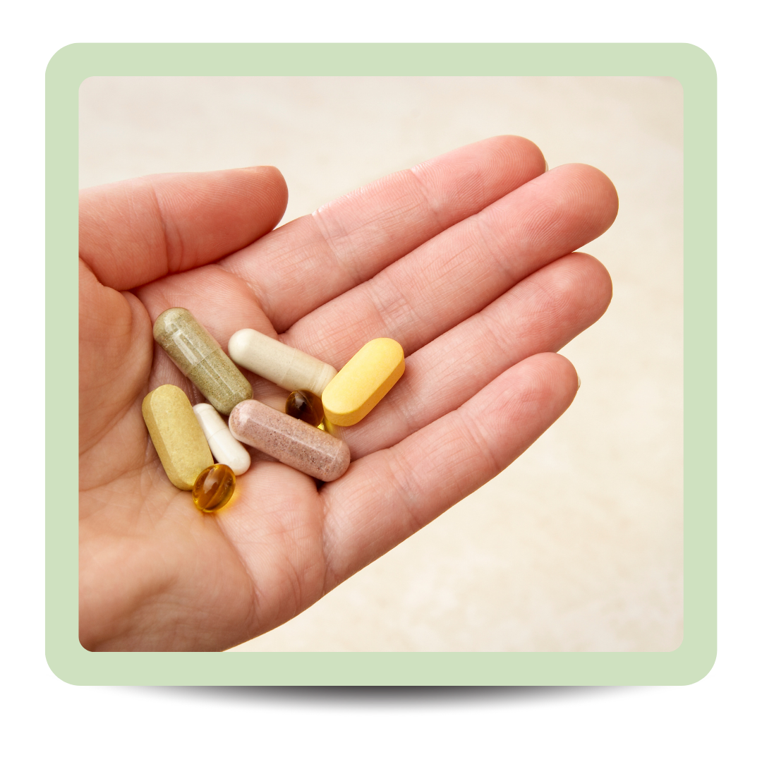 Hand holding various pills and capsules of different shapes and colors.