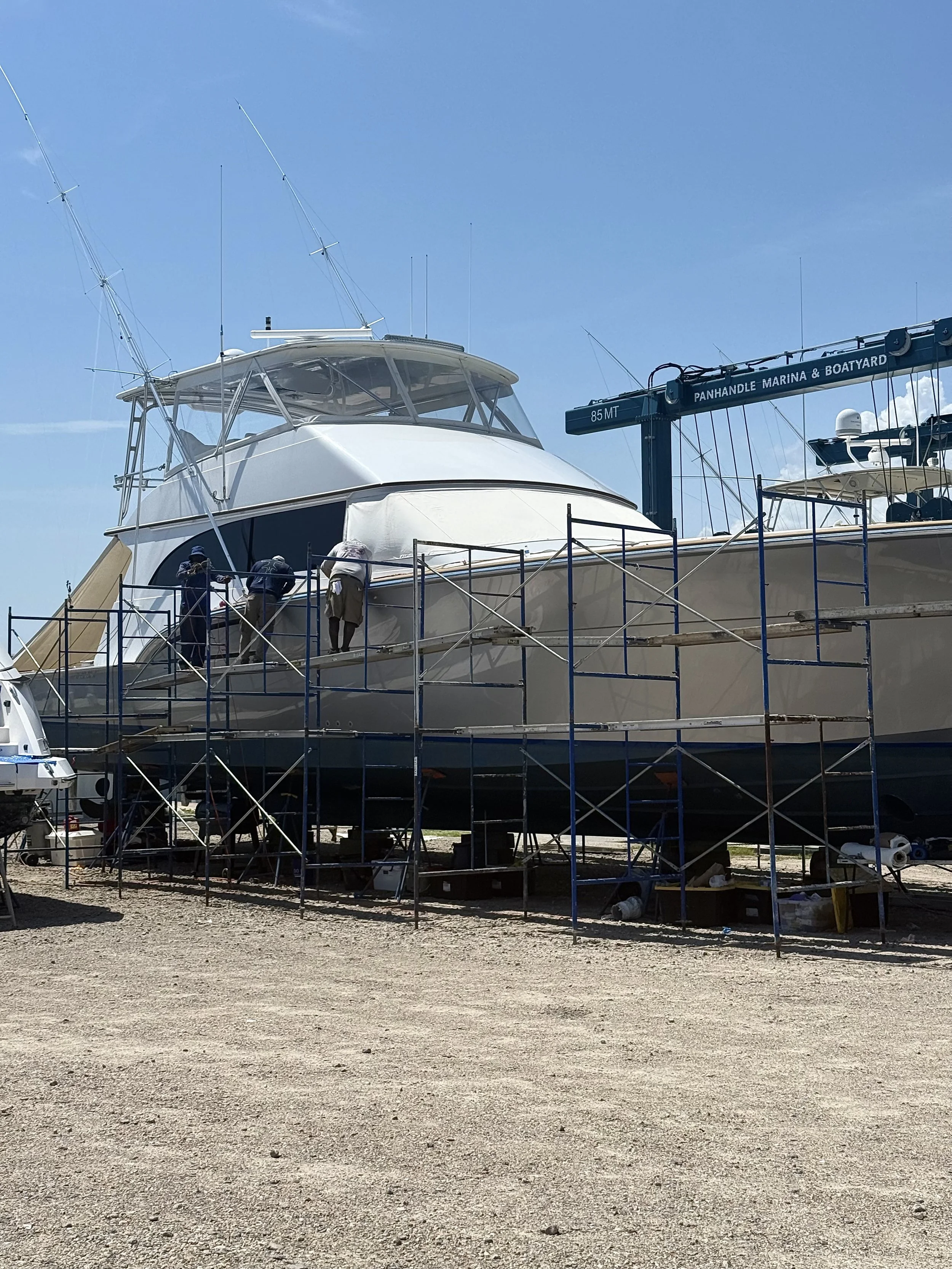 Picture of 3 crew members on scaffolding repairing a larger boat/yacht.