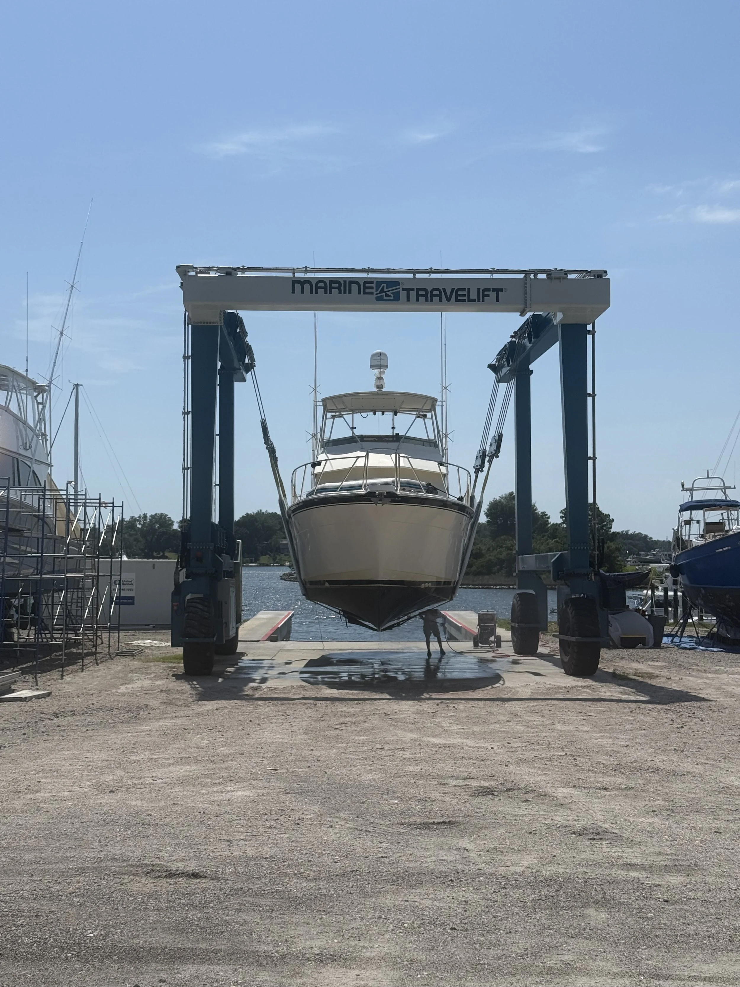 the front of a boat being lifted into a marine travel lift while above the ground about to be moved back into the water to launch