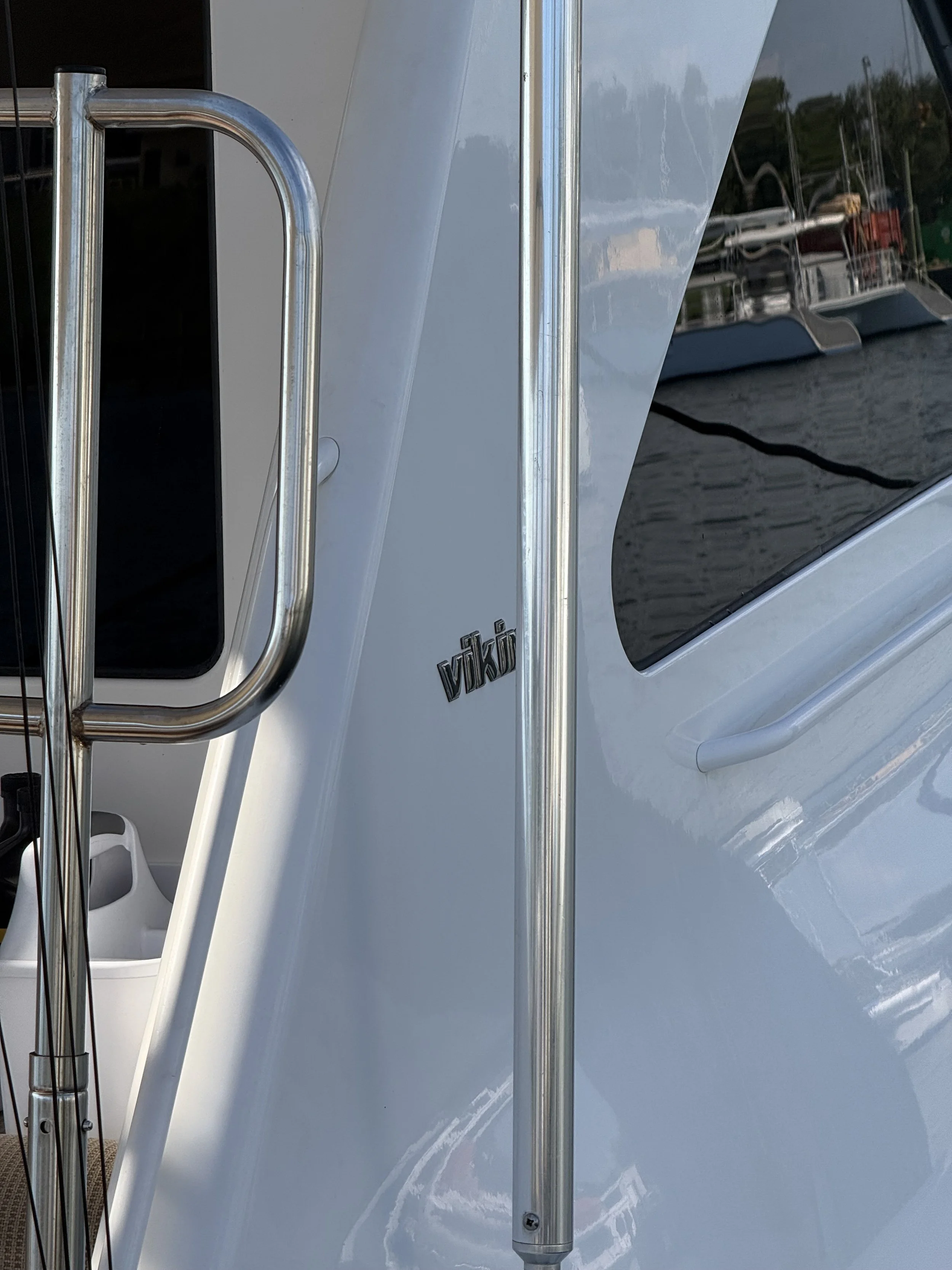 Up close shot of the Viking Brand name on a white boat with parts of the boat's windows and door included in the picture.
