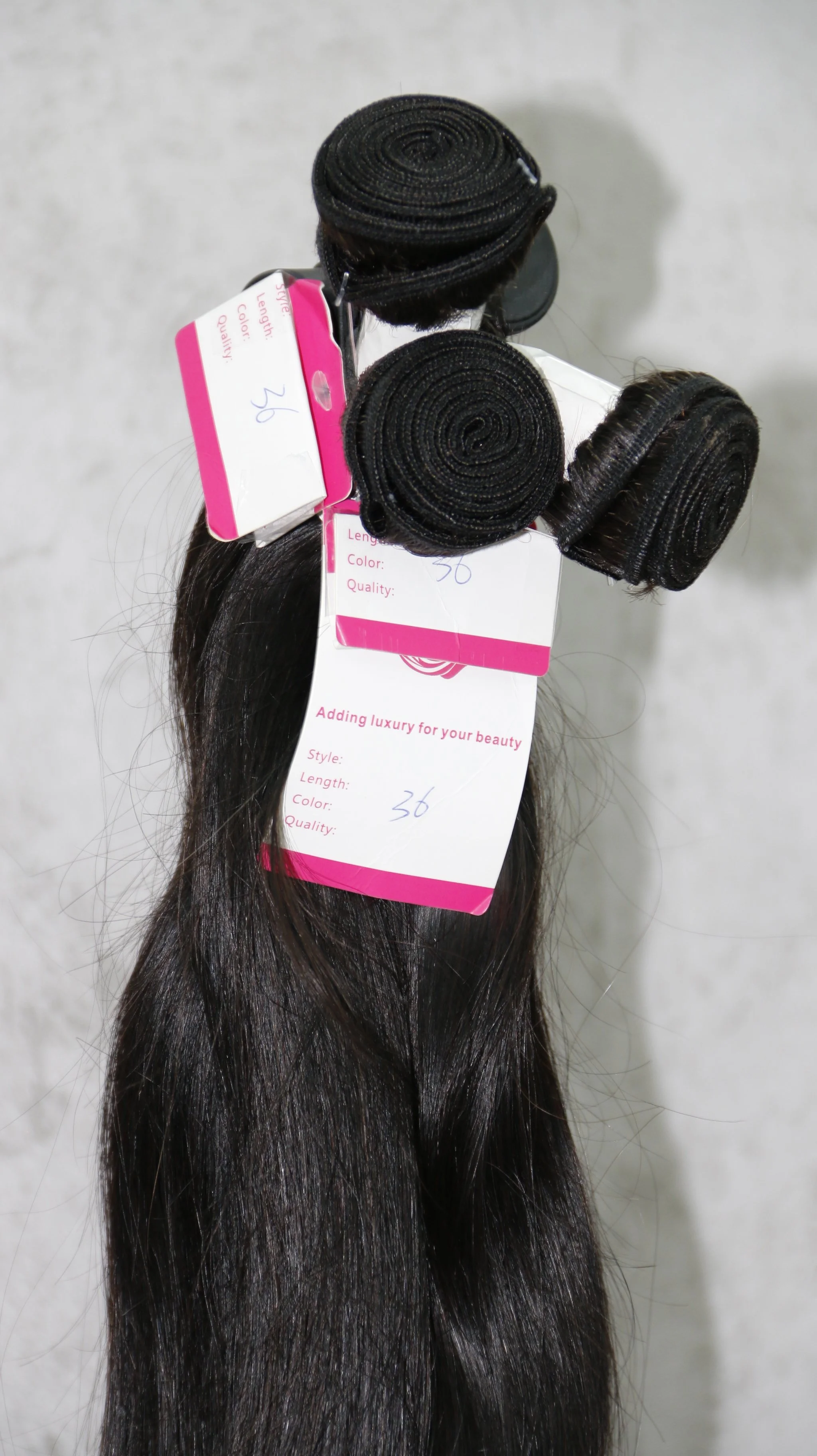 Bundle of dark brown or black hair extension weaves with tags indicating length and style.