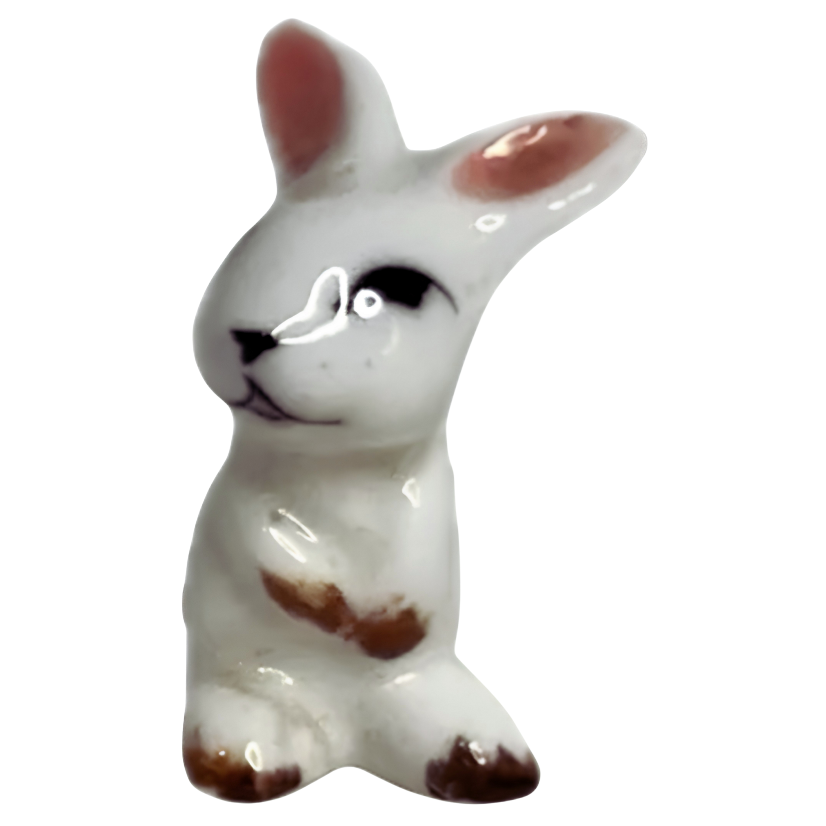 Ceramic animal figurine resembling a dog or fox, predominantly white with brown and black markings, against a black background.