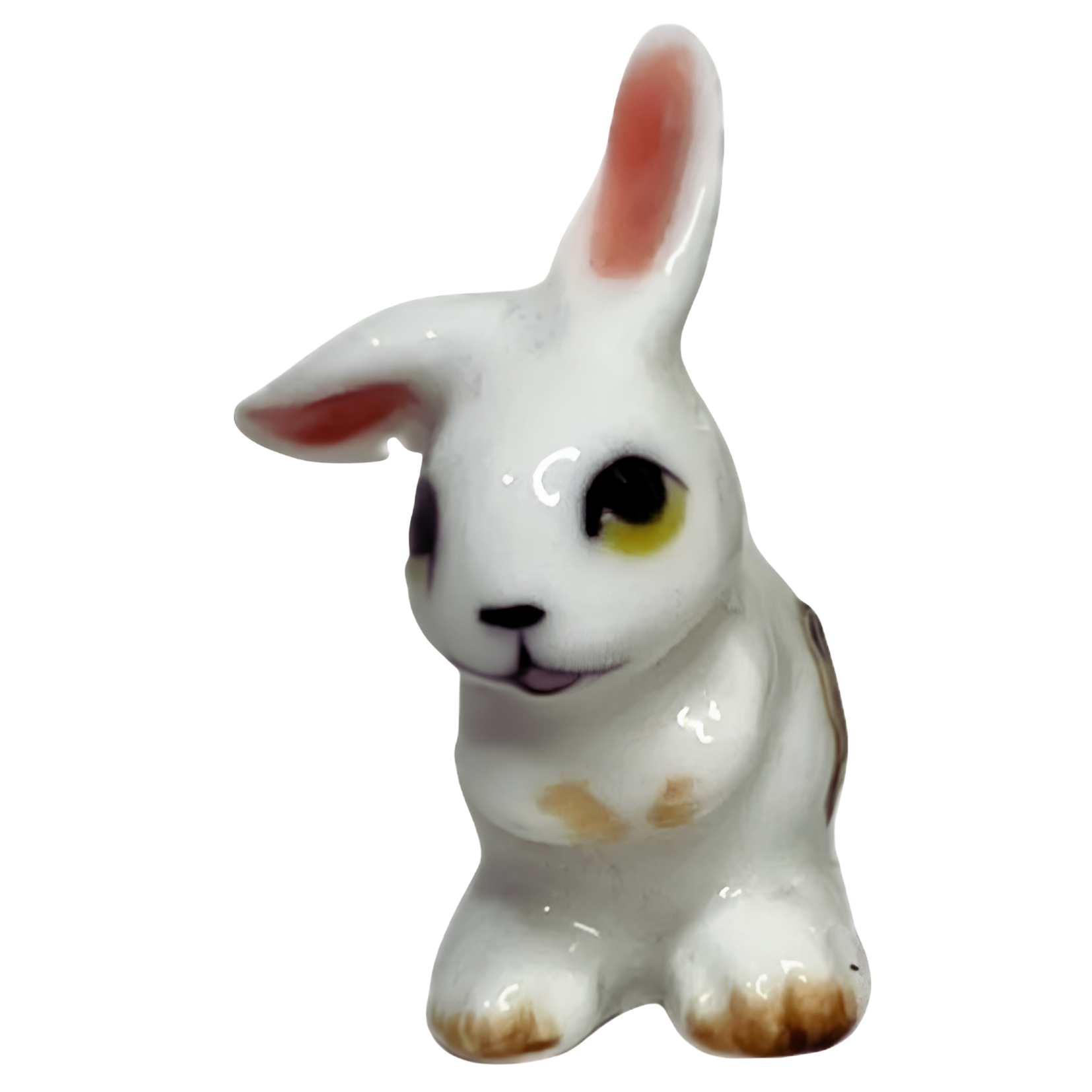 A ceramic figurine of a white rabbit with pink ears, black and yellow eyes, and brown accents on its paws and nose, positioned against a black background.