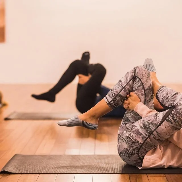 People doing a seated yoga stretch on exercise mats in a studio