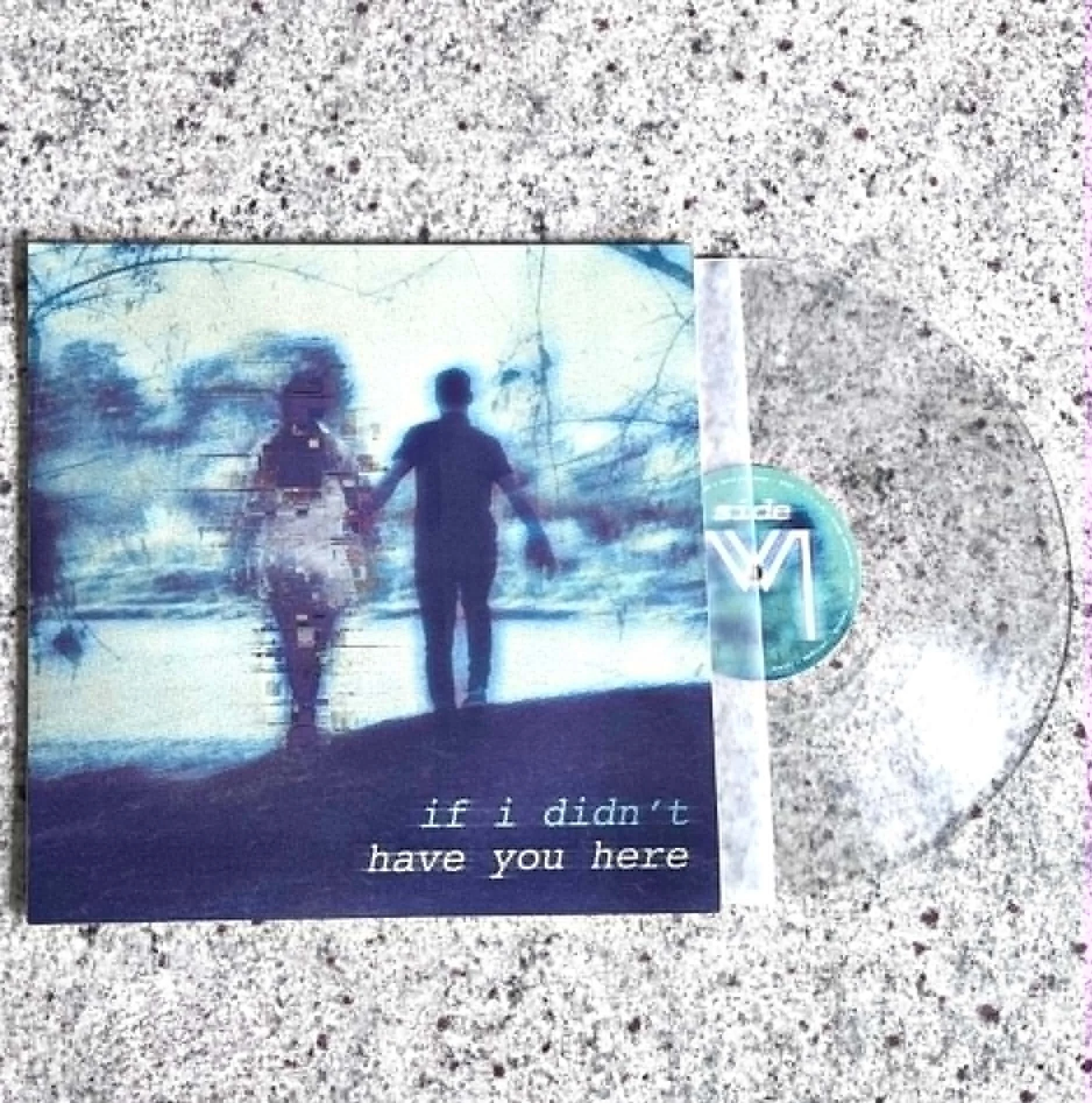 A picture of a clear vinyl record titled 'if I didn't have you here' resting on a speckled granite surface. The cover features an image of two people walking in a forest with a blue and green color tone.
