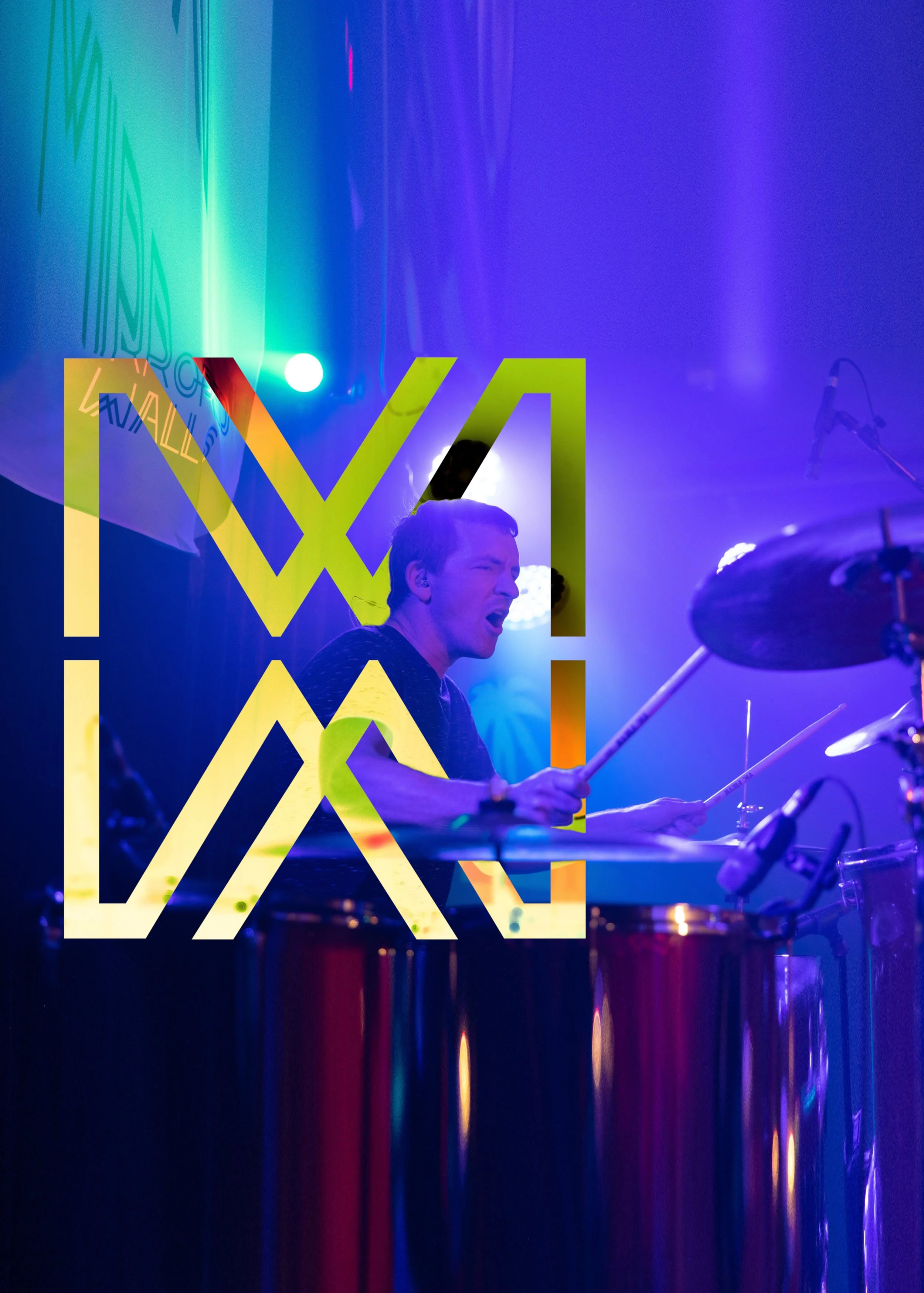 A musician playing drums on stage with colorful lighting and a large, semi-transparent overlay of the logo 'MW' in yellow, orange, blue, and black.