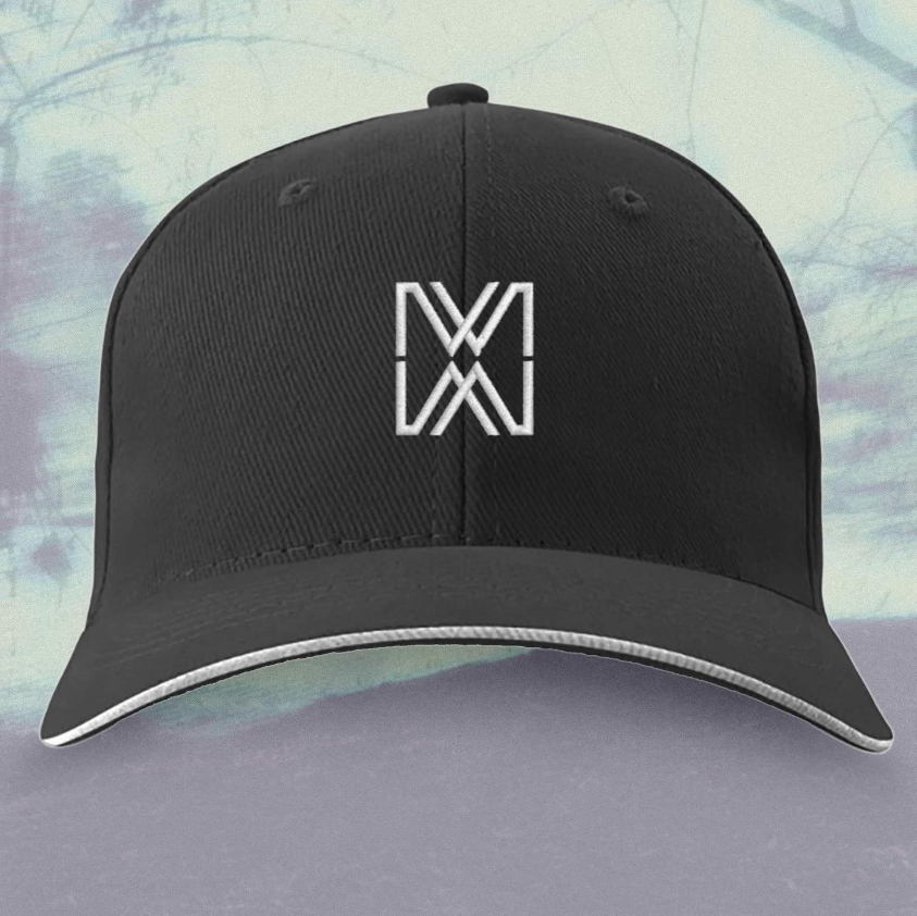Black baseball cap with a white geometric logo on the front, against a blurred outdoor background.