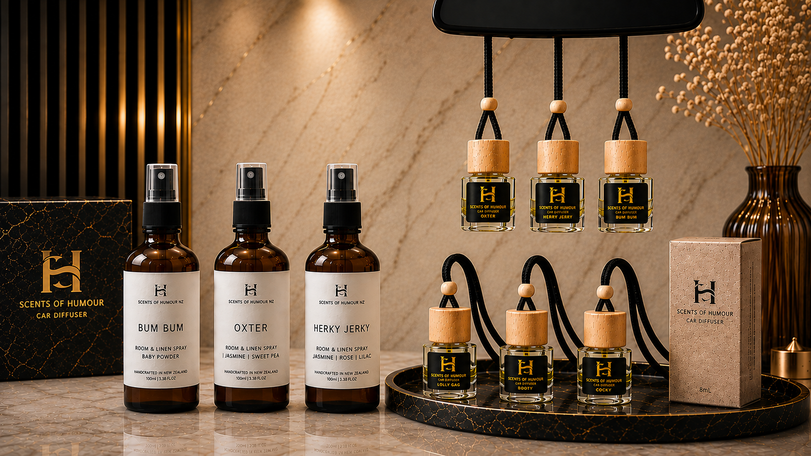 Luxury display of scents and room sprays from 'Scents of Humour' brand, including three spray bottles labeled 'Bum Bum,' 'Oxter,' and 'Herky Jerky,' with smaller fragrance bottles hanging and on the tray, decorated with elegant black and gold packaging and a marble surface.