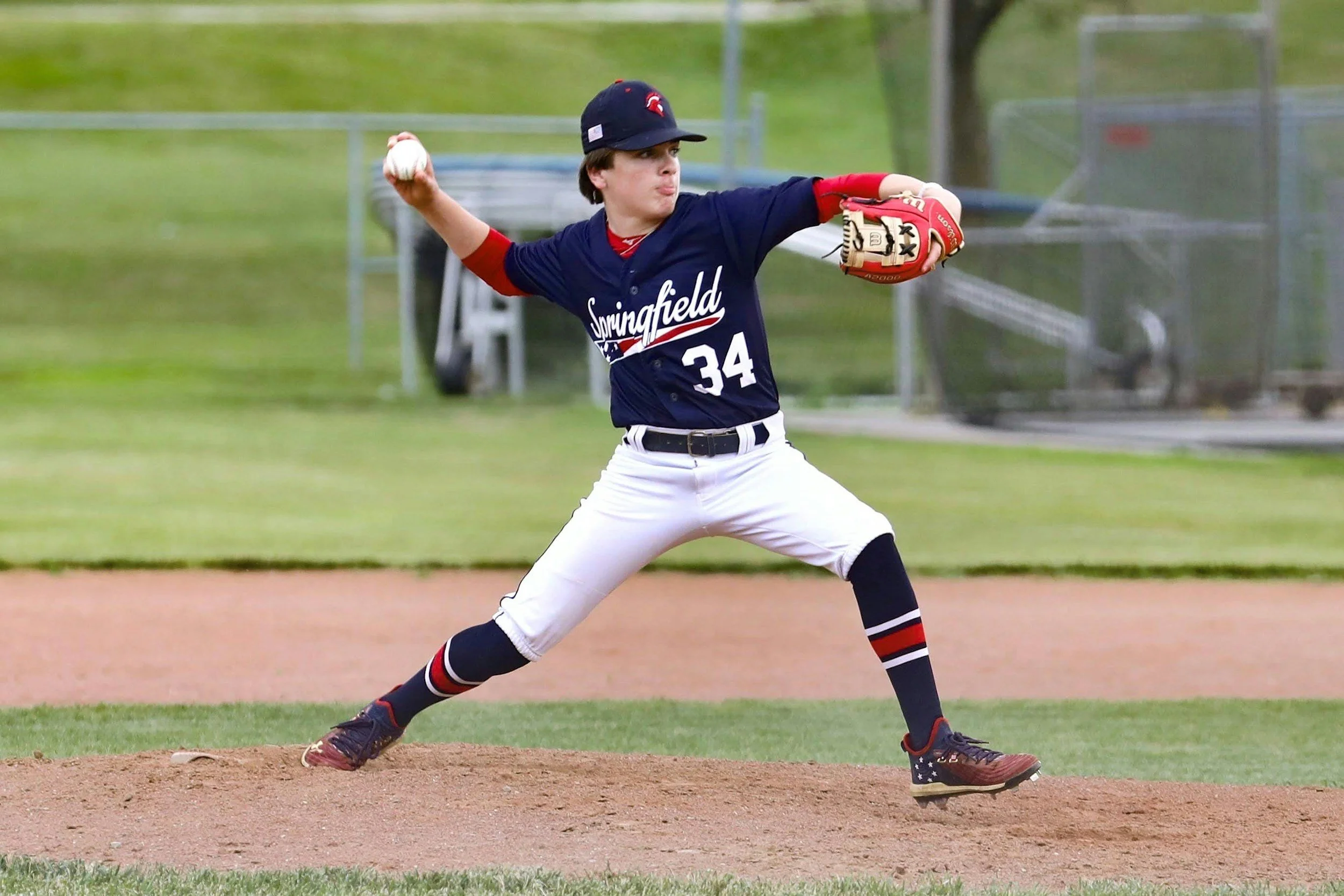 Joven jugador de béisbol lanzando la pelota en un campo de béisbol.