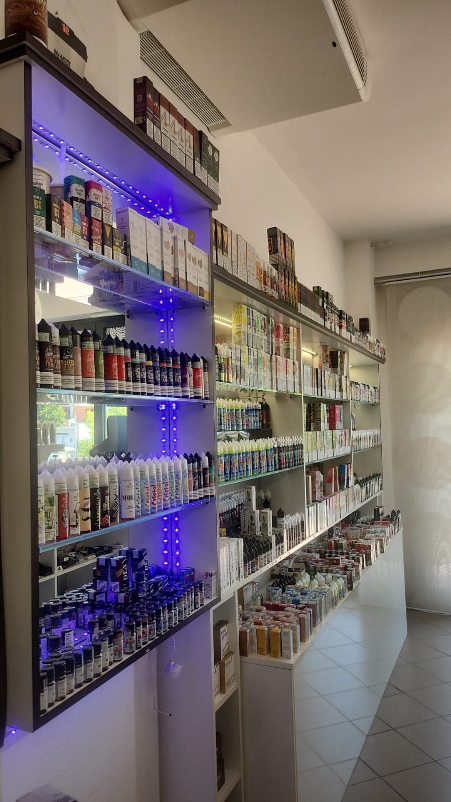 Scaffale con varie confezioni di prodotti e liquidi, tra cui spray e flaconi, in un negozio.
