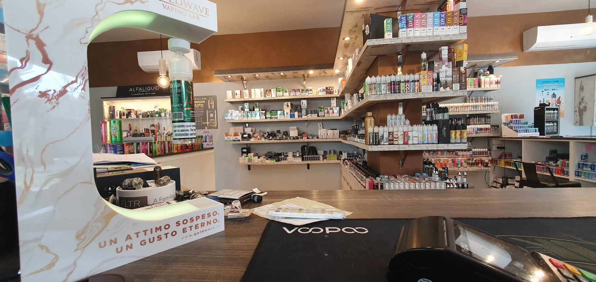 Interno di un negozio o laboratorio dedicato alla produzione o vendita di vaporizzatori e prodotti correlati, con scaffali pieni di e-liquidi e accessori.