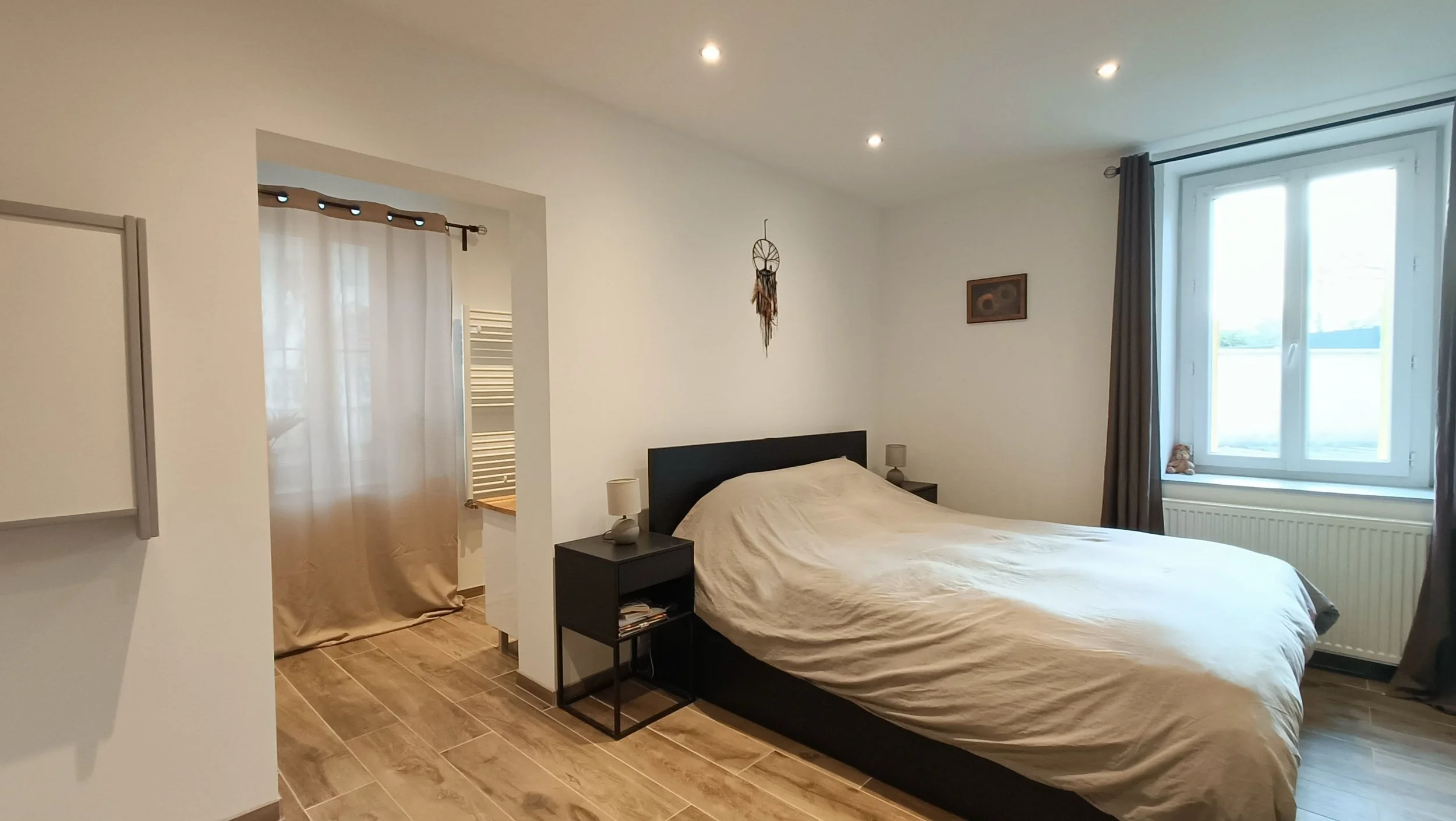 Chambre à coucher avec un lit, deux lampes de chevet, une fenêtre avec rideaux et une décoration murale