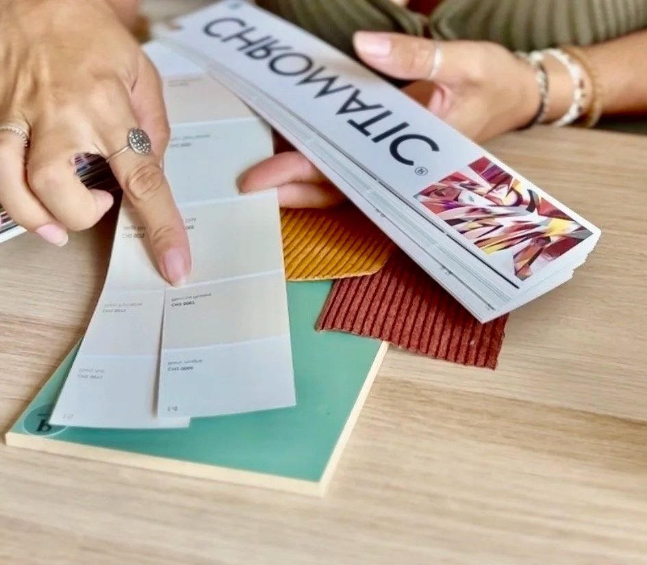 Choix de couleur end décoration d'intérieur sur un nuancier chromatic avec textures sur un bureau ennemi bois, tenu par des mains de femmes, la décoratrice Ezka Déco