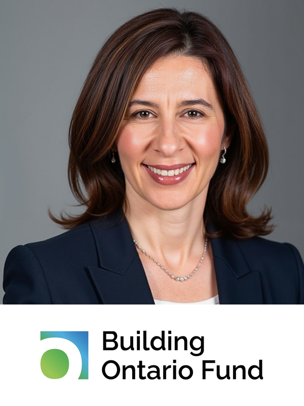 A professional woman with shoulder-length brown hair, wearing a navy blazer, white shirt, and jewelry, smiling against a gray background, with the Building Ontario Fund logo at the bottom.