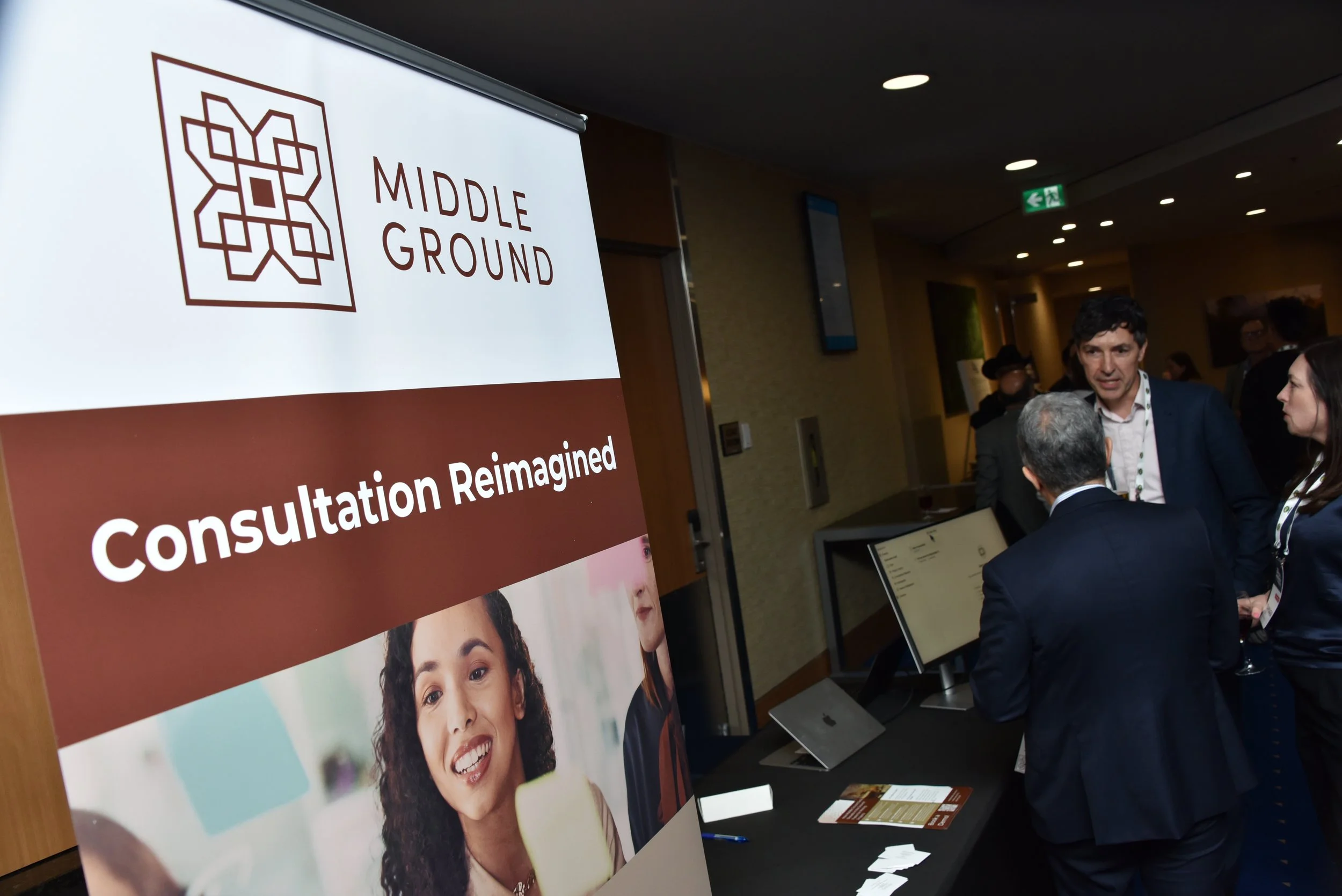 Conference or seminar registration area with a large display and people talking.