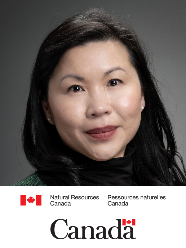 Close-up portrait of a woman with long black hair, wearing a black turtleneck, smiling gently against a gray background with a logo for Natural Resources Canada and the Canadian flag at the bottom.