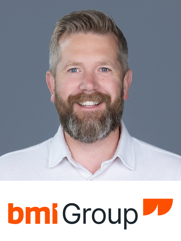 A smiling middle-aged man with a beard and short, light brown hair, wearing a white collared shirt, against a gray background, with the bmi Group logo at the bottom.