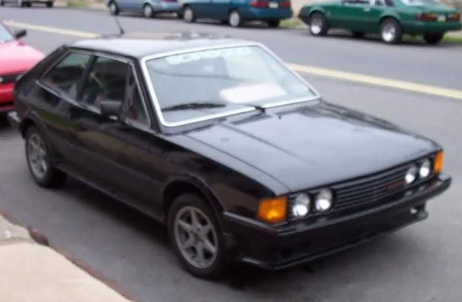 A black 1980 Volkswagen Scirocco S with a Zender body kit and grille on Borbet wheels, parked at a curb.