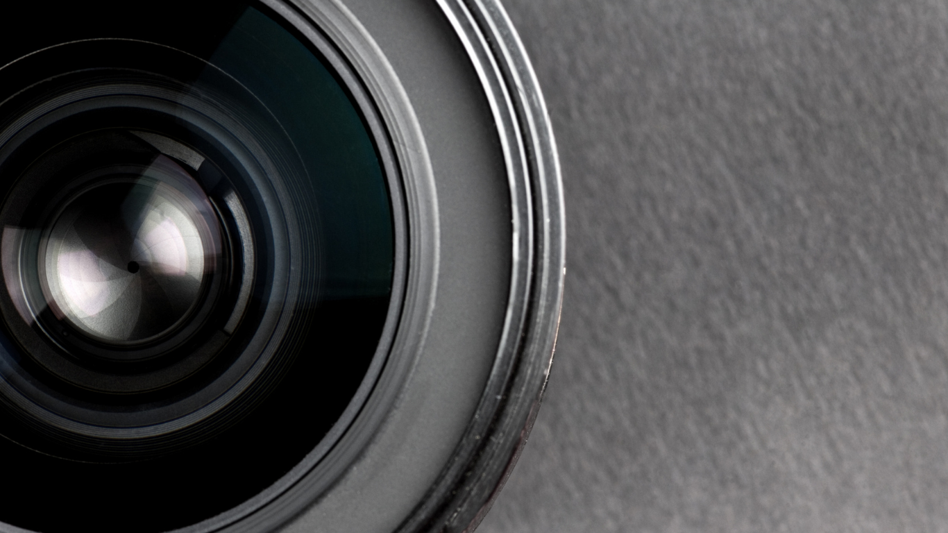 Close-up of a camera lens on a gray textured background.