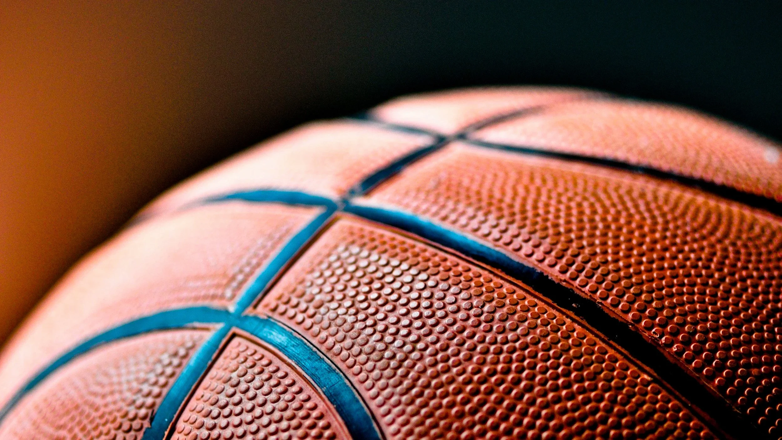 Dettaglio di un pallone da basket con la superficie di pelle arancione e dettagli blu.