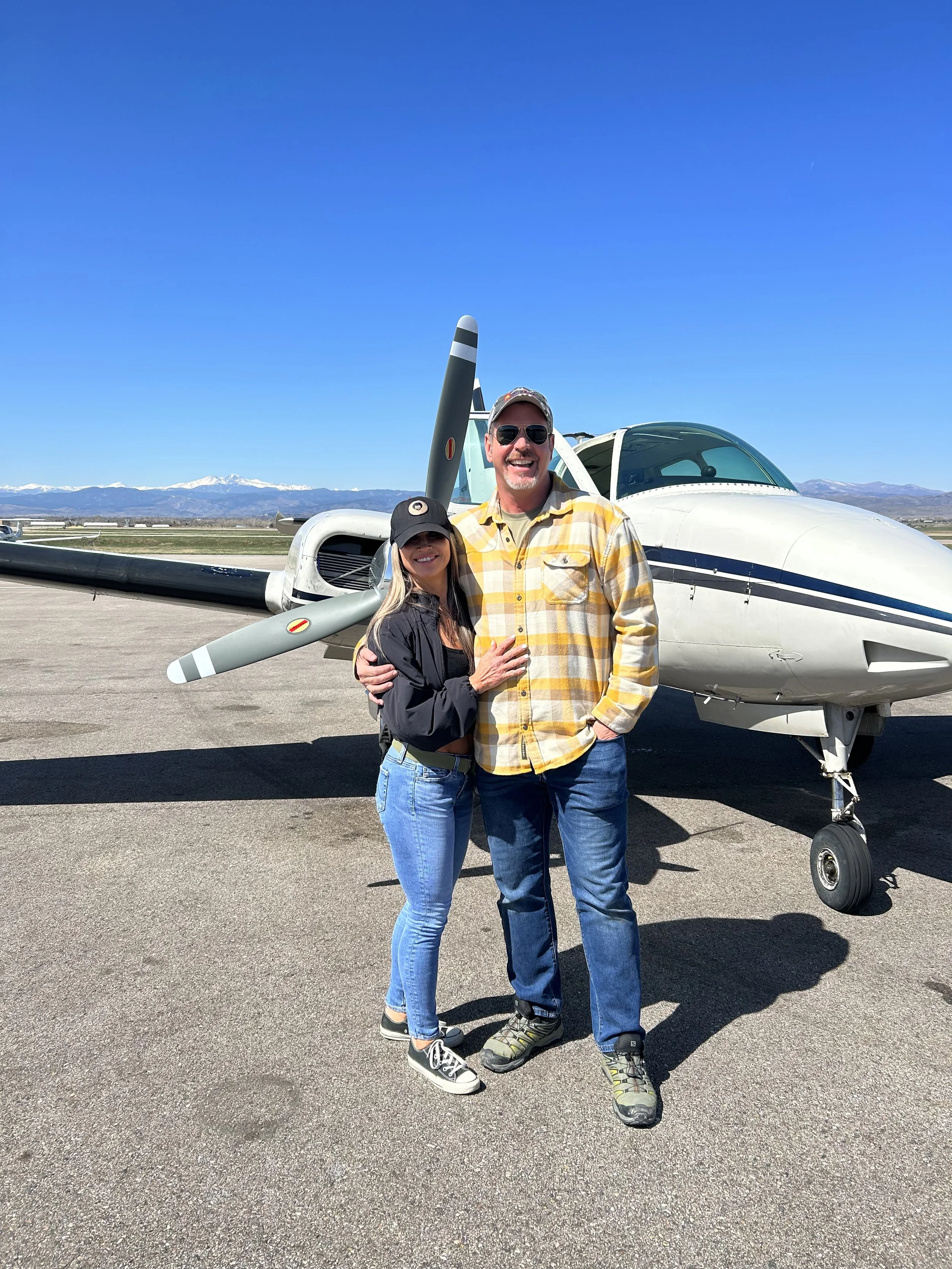 Two people standing beside an aircraft on the airport ramp.