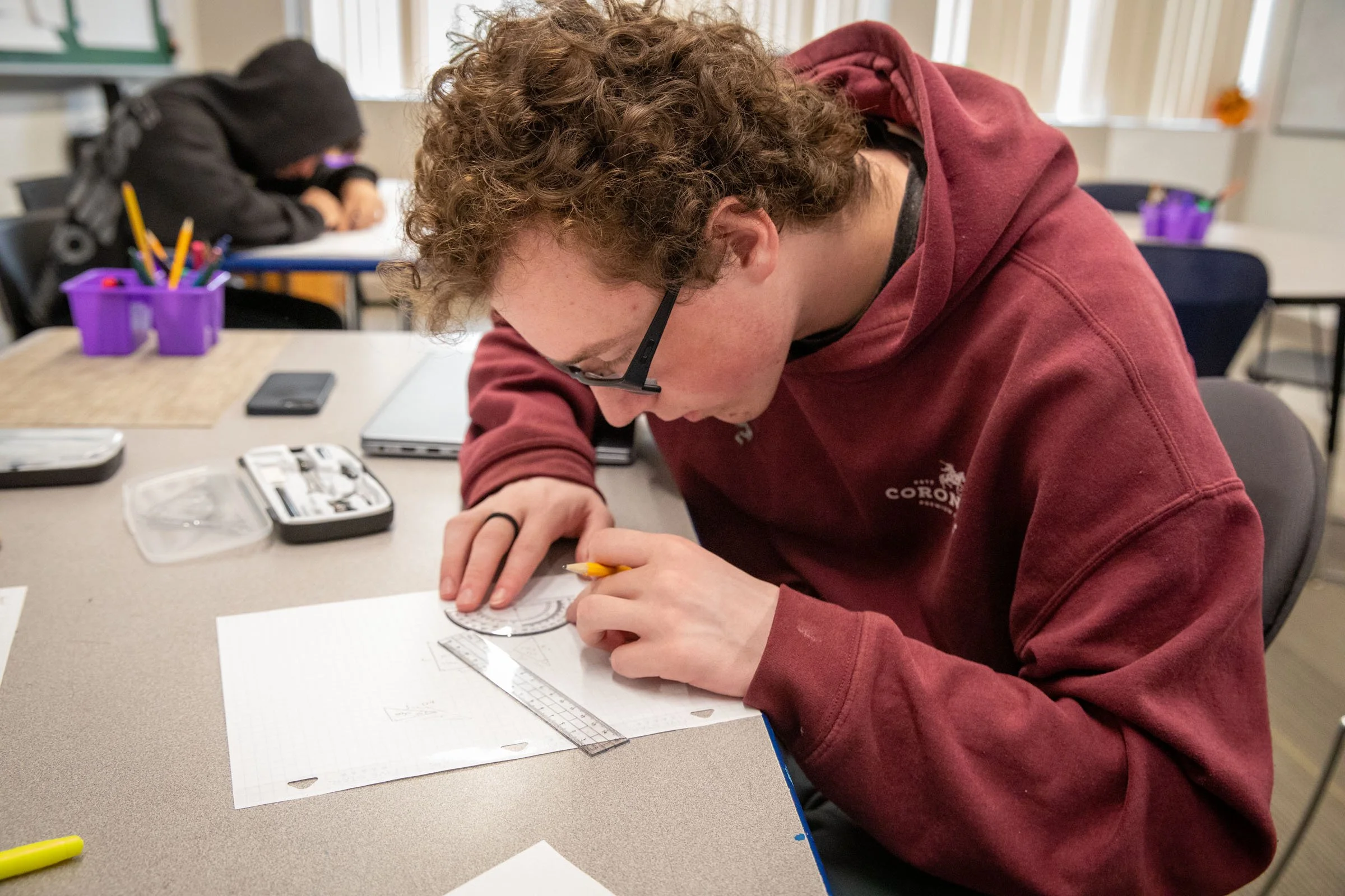 A Tremont School student working on a geometric drawing project at his desk in class.