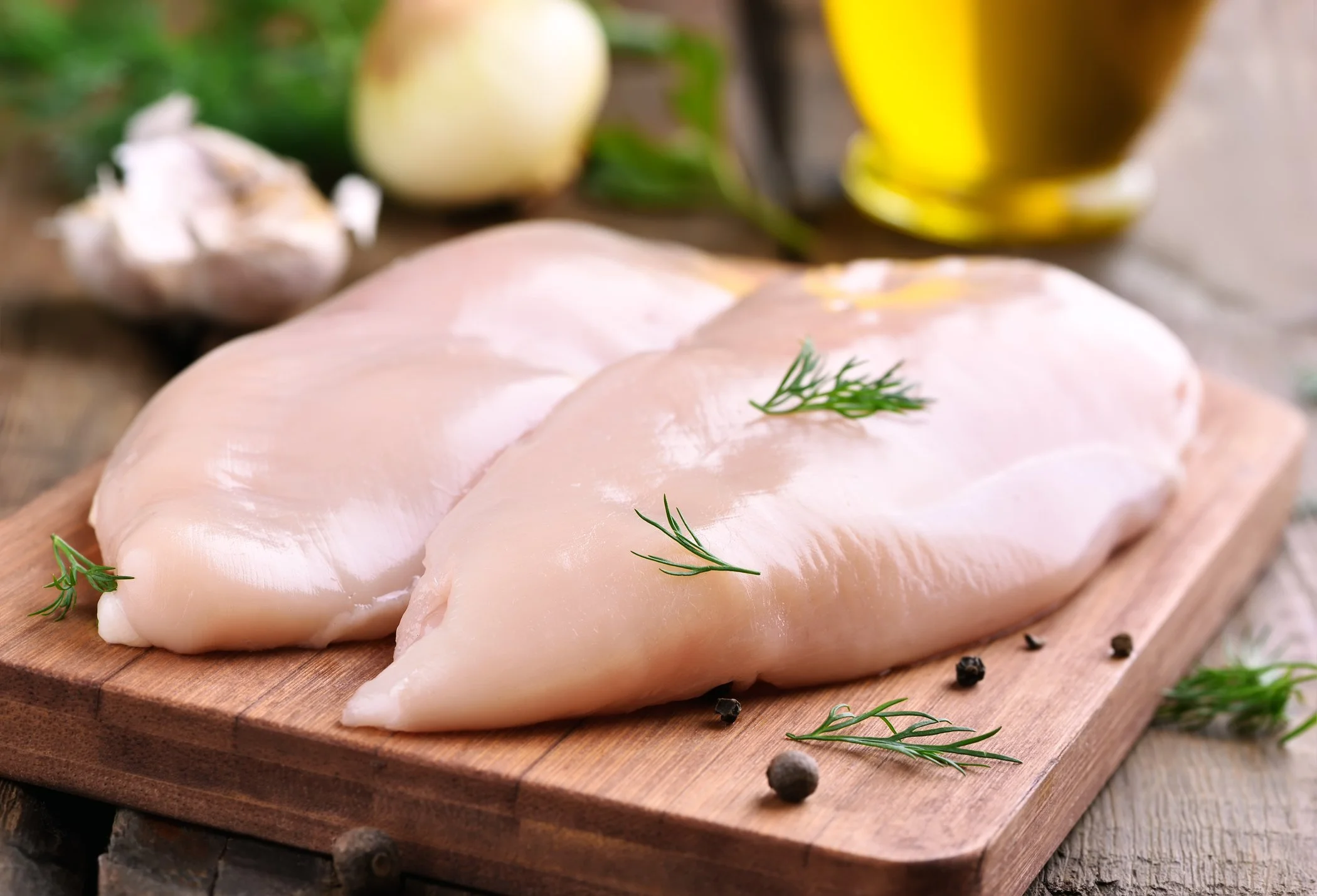 Chicken breast fillets with rosemary on a wooden board