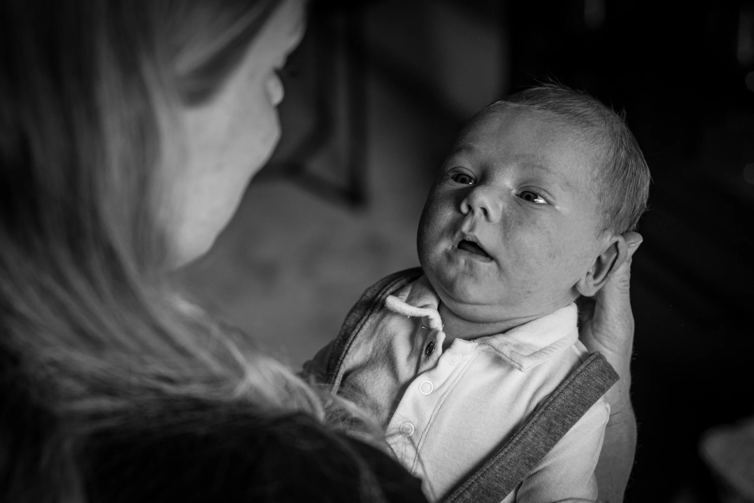 Black and white photo of a woman holding a baby facing her, both showing tenderness and connection.