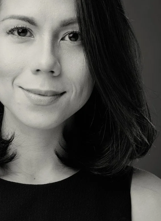 Close-up black-and-white portrait of a woman with dark hair, smiling subtly.