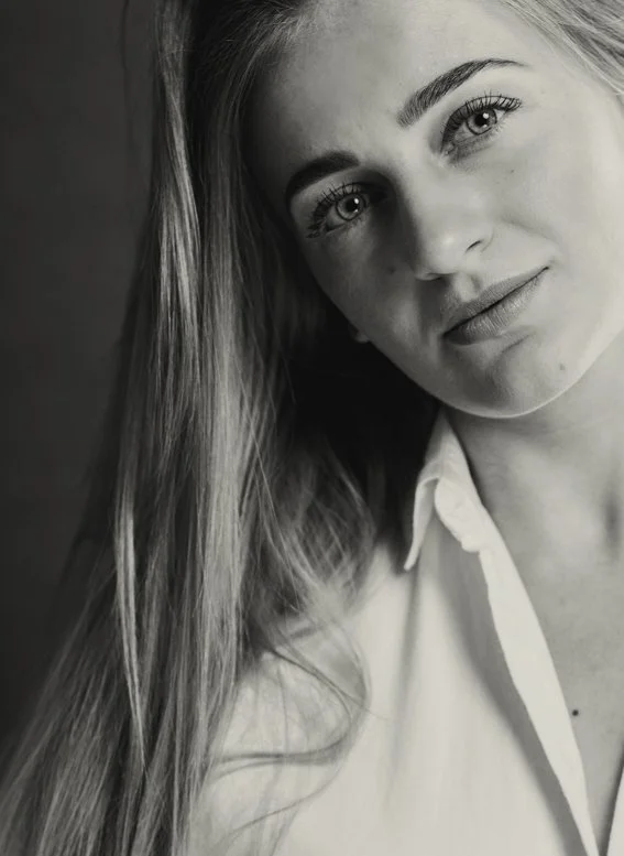 Black and white close-up portrait of a young woman with long hair, light eyes, and a gentle smile.