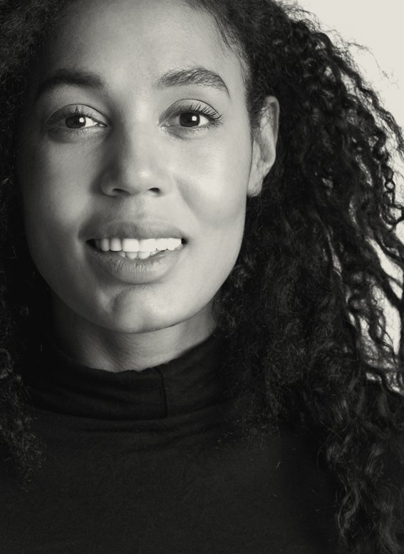 Close-up black and white portrait of a woman with curly hair, smiling.