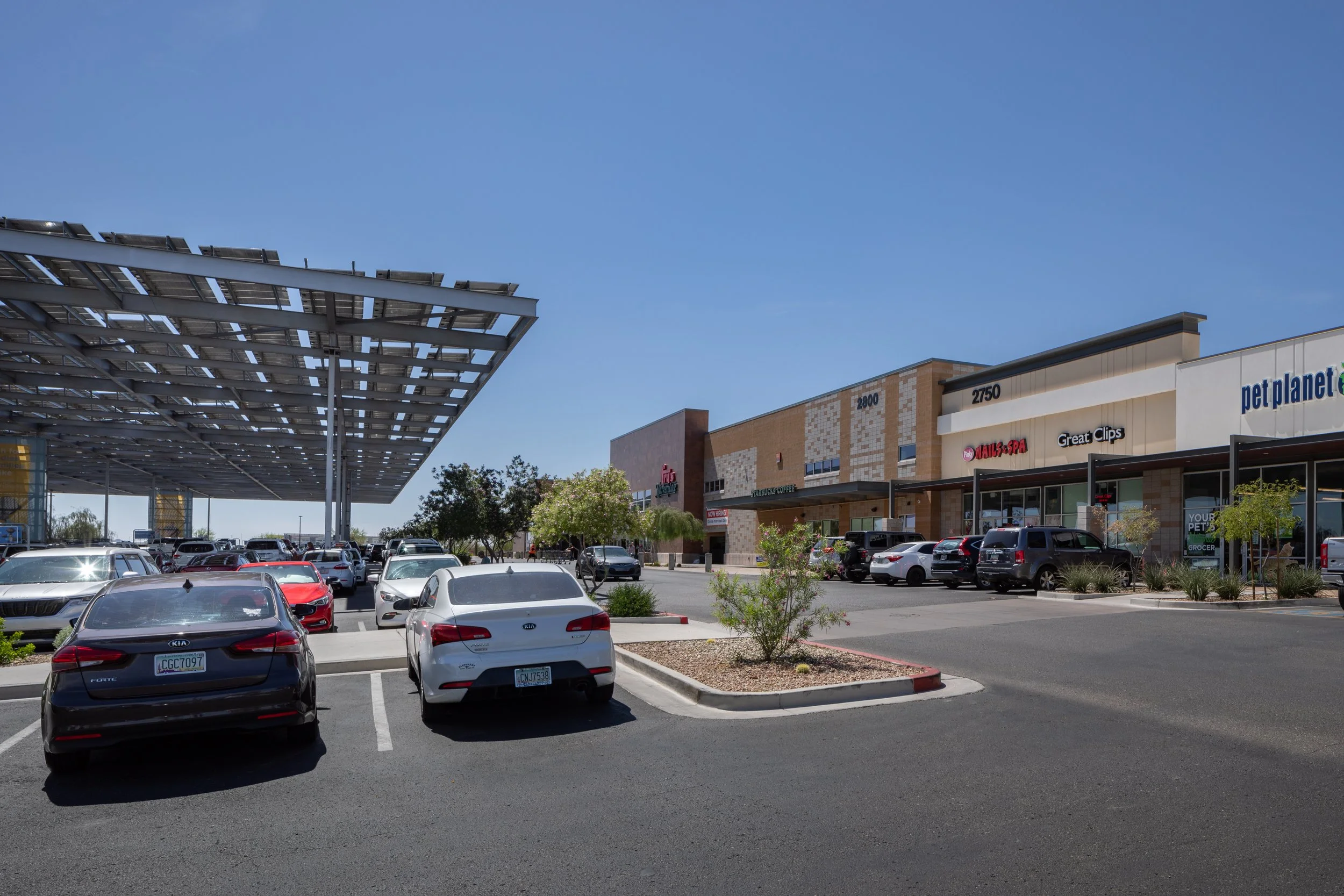 Canyon Crossroads shopping center in Phoenix, Arizona, featuring retail storefronts and solar-panel shade structures over the parking area.