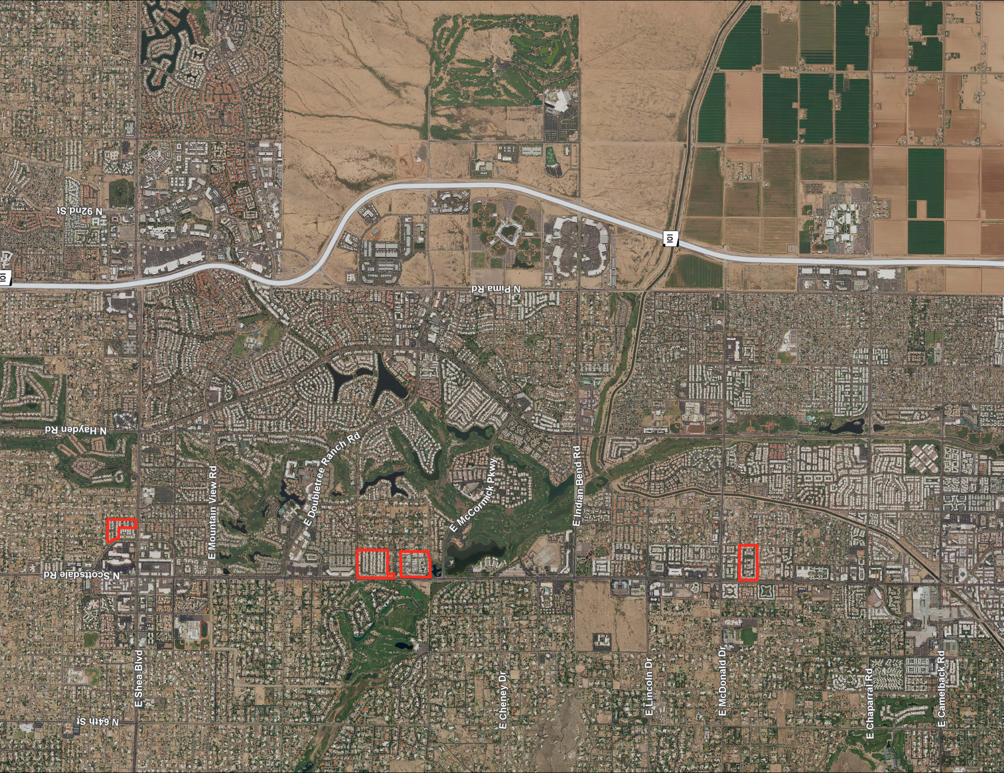A satellite map of a region with residential neighborhoods, green fields, roads, and a golf course. Several areas are marked with red outlines.
