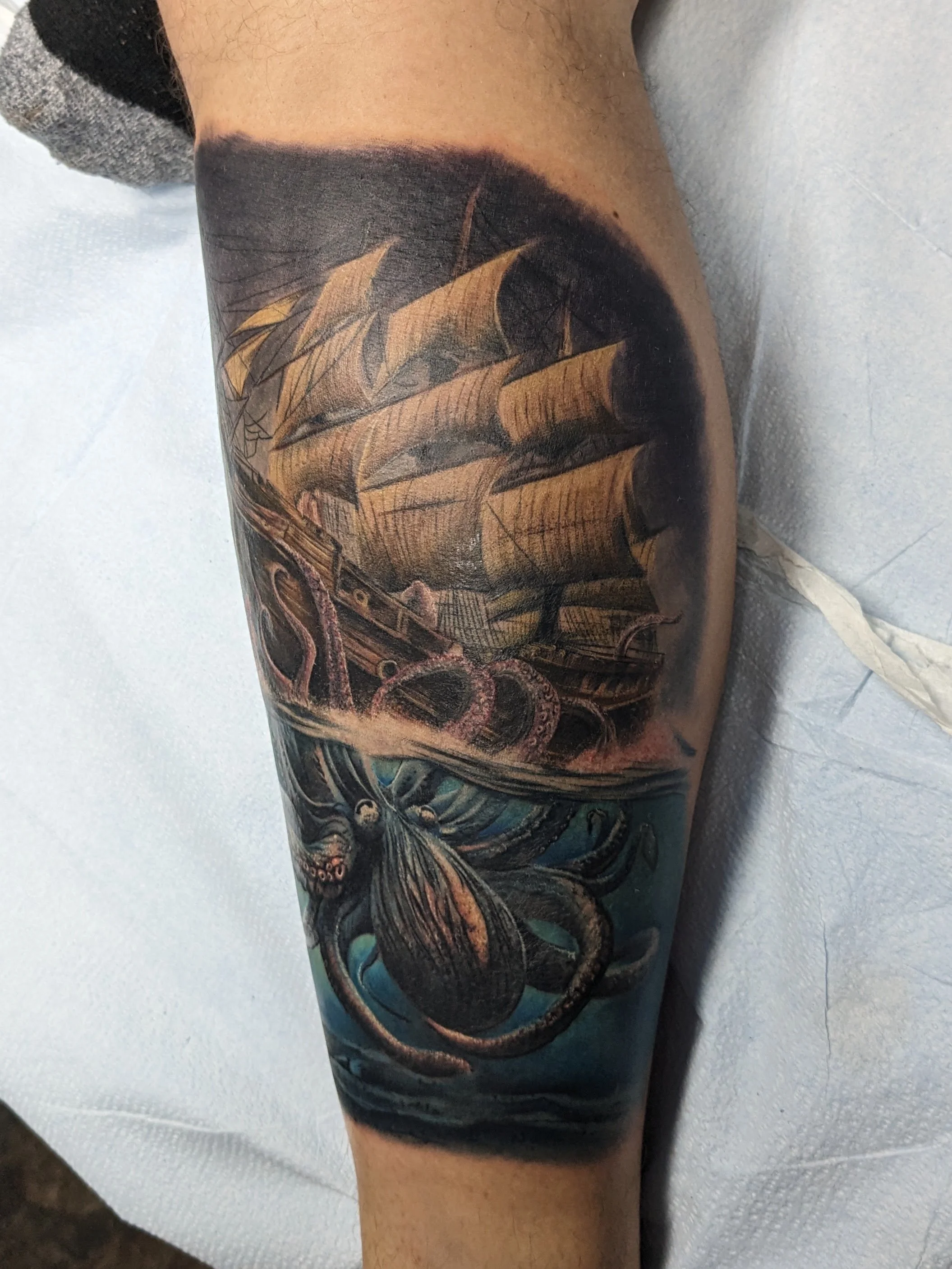 A tattoo of a realistic spelling of the word 'STRENGTH' on a person's arm, with an oil rig and orange sunset in the background.