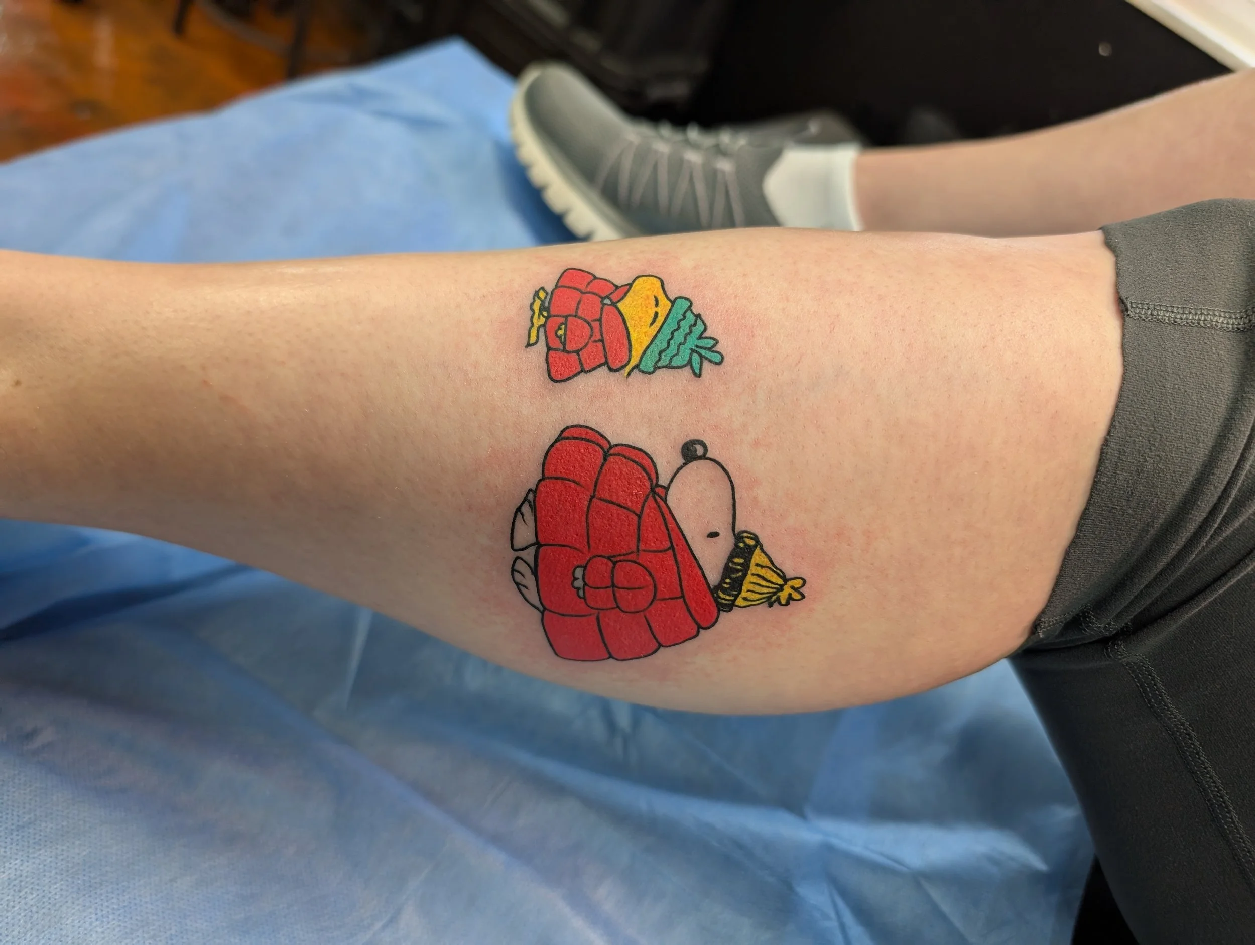 Colorful cartoon tattoo of a crab, a slice of lemon, and a fish on a person's forearm.