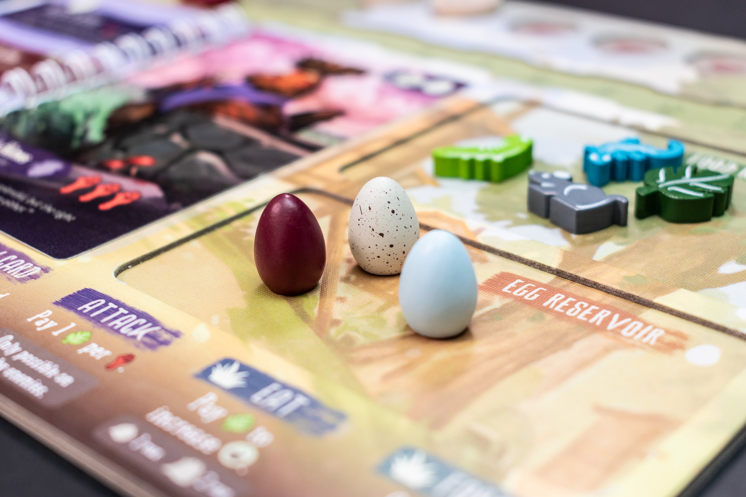 Colorful game board with three decorated eggs and game pieces on it.