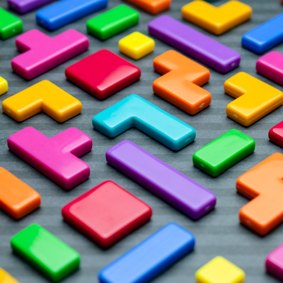Colorful Tetris-shaped game pieces scattered on a gray surface.