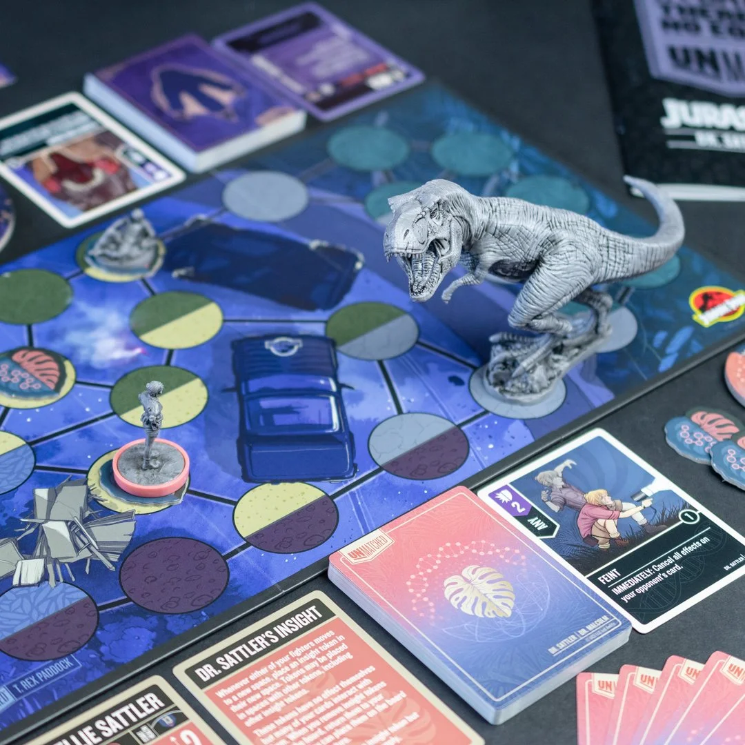 A board game setup featuring a T-Rex figurine, playing cards, game tokens, and a game board with connected circular spaces. The game appears to involve strategic movement and cards with illustrations and text.